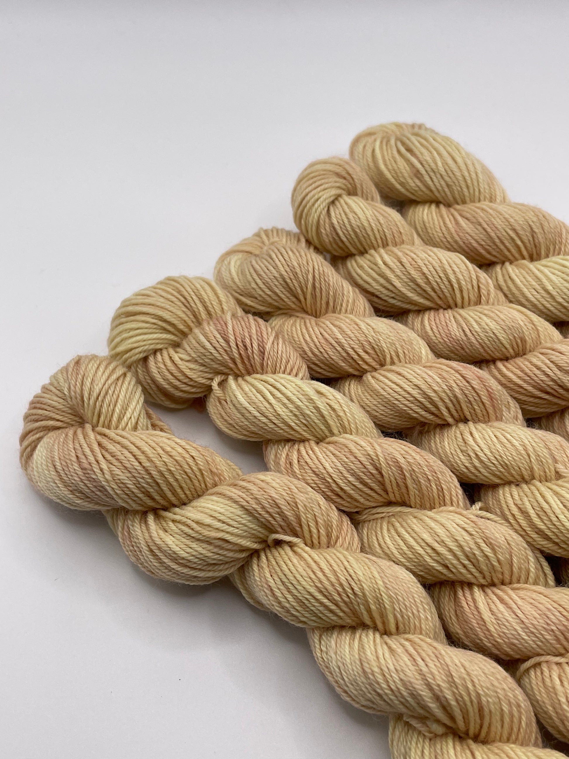 Creamy peach yarn mini skeins on a white background