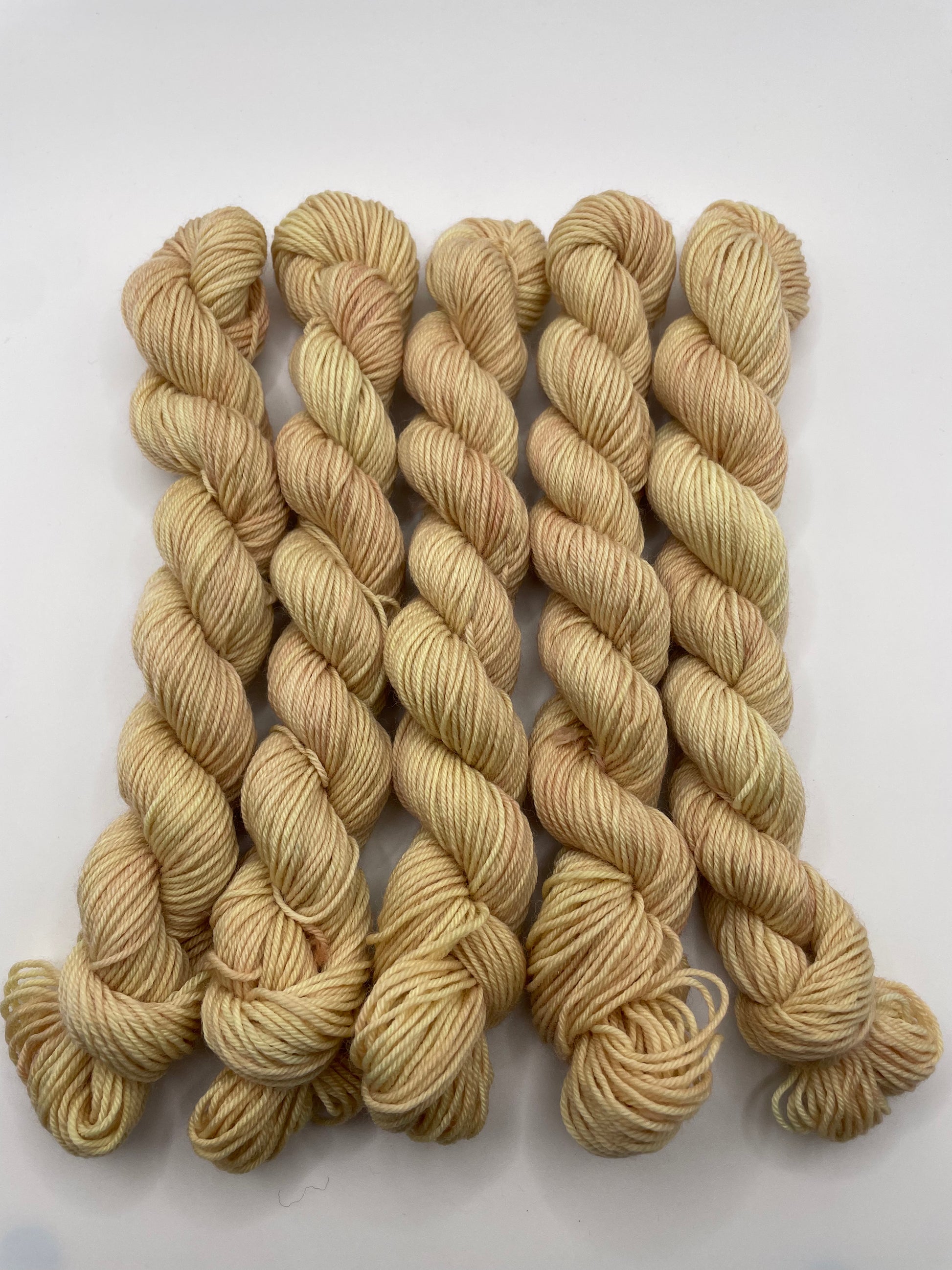 Creamy peach yarn mini skeins on a white background