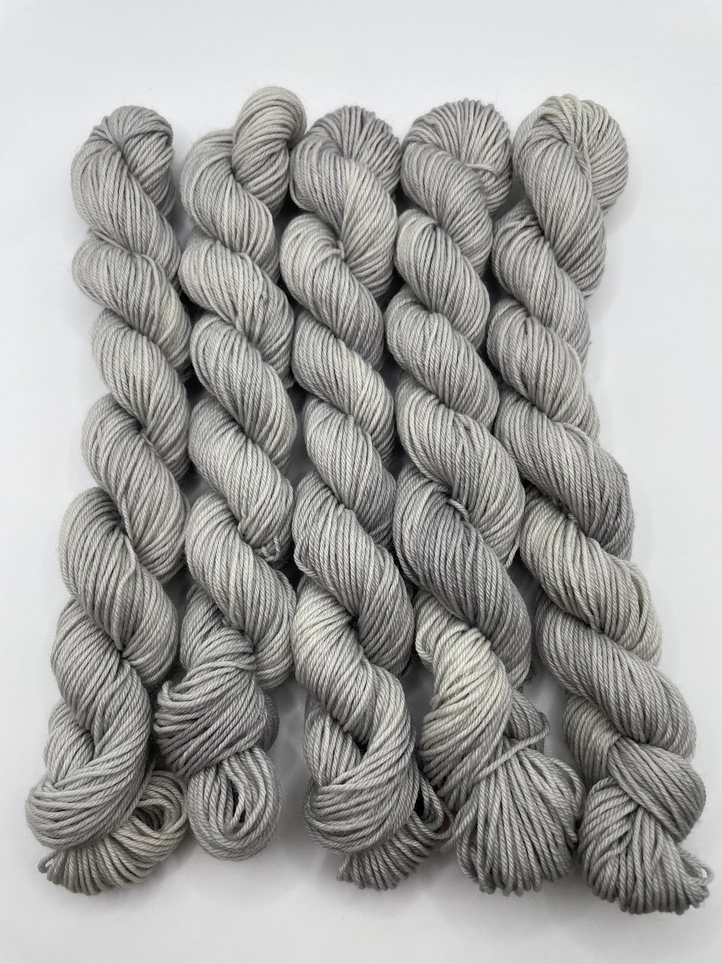 Grey yarn mini skeins on a white background
