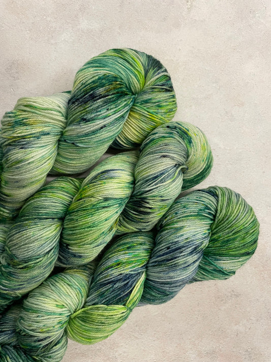 3 skeins of hand dyed sock yarn featuring shades of green, blue and navy