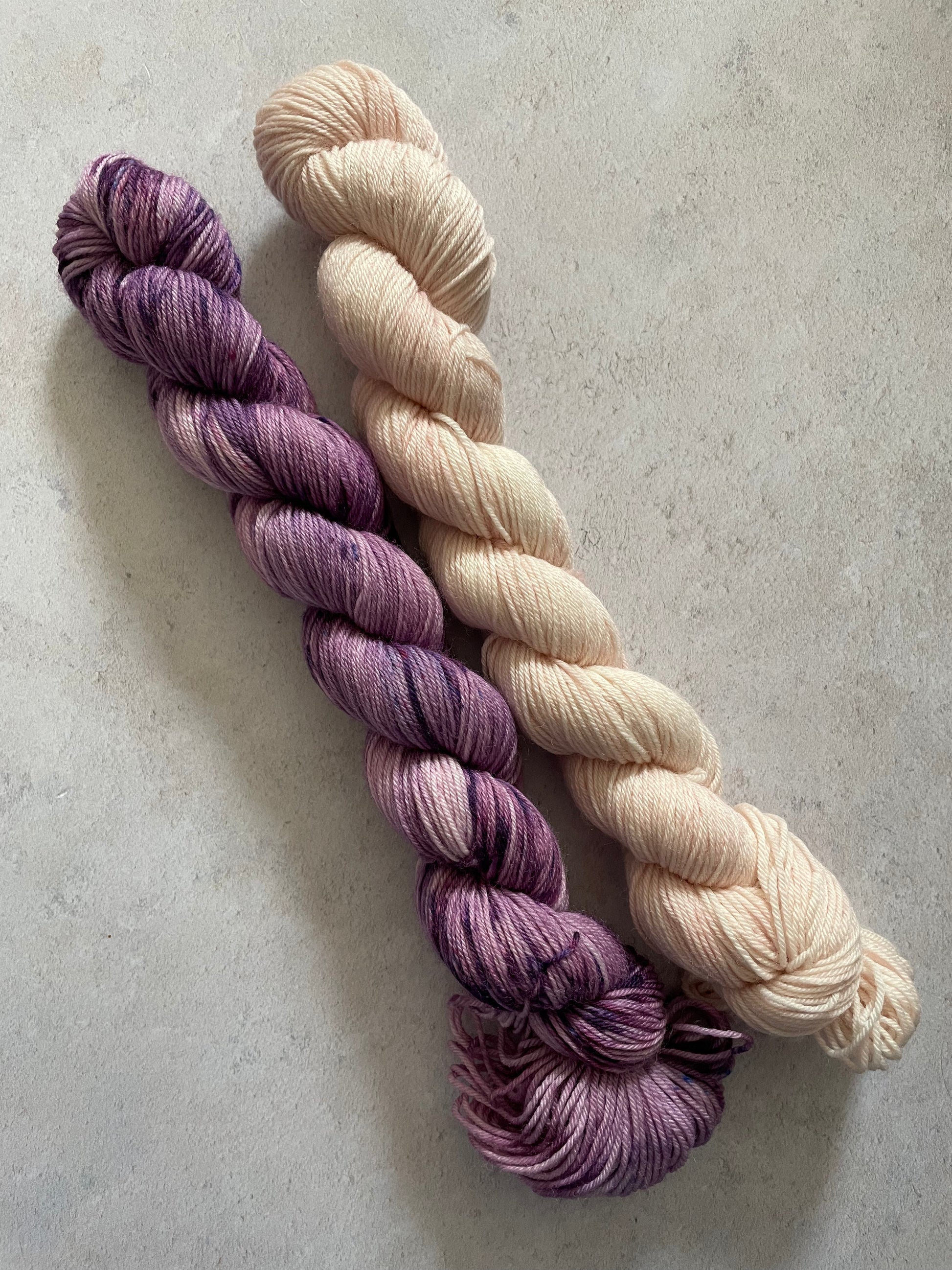 One 50g variegated purple skein and one 50g pale pink skein
