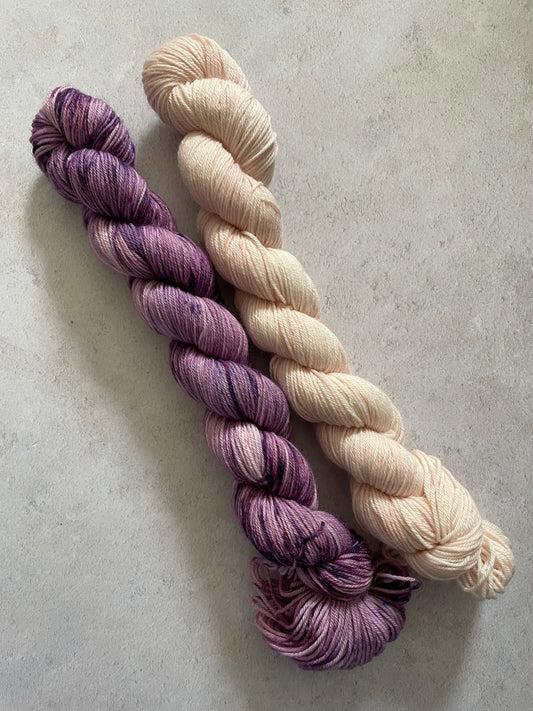 One 50g variegated purple skein and one 50g pale pink skein