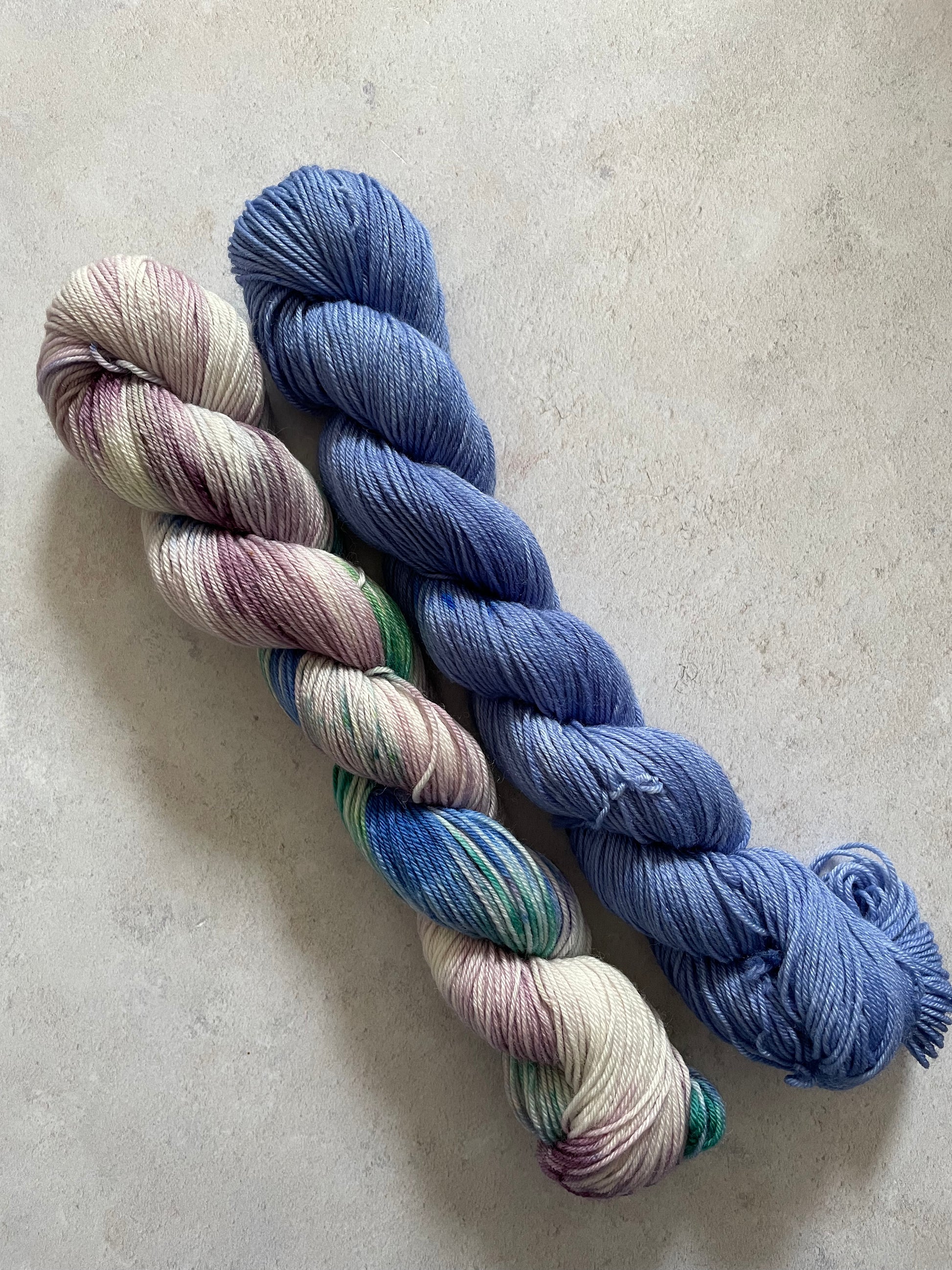 One 50g variegated lilac blue and green skein and one 50g blue skein