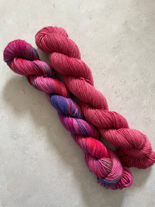 One 50g variegated deep pink and multicoloured skein and one 50g pink red skein