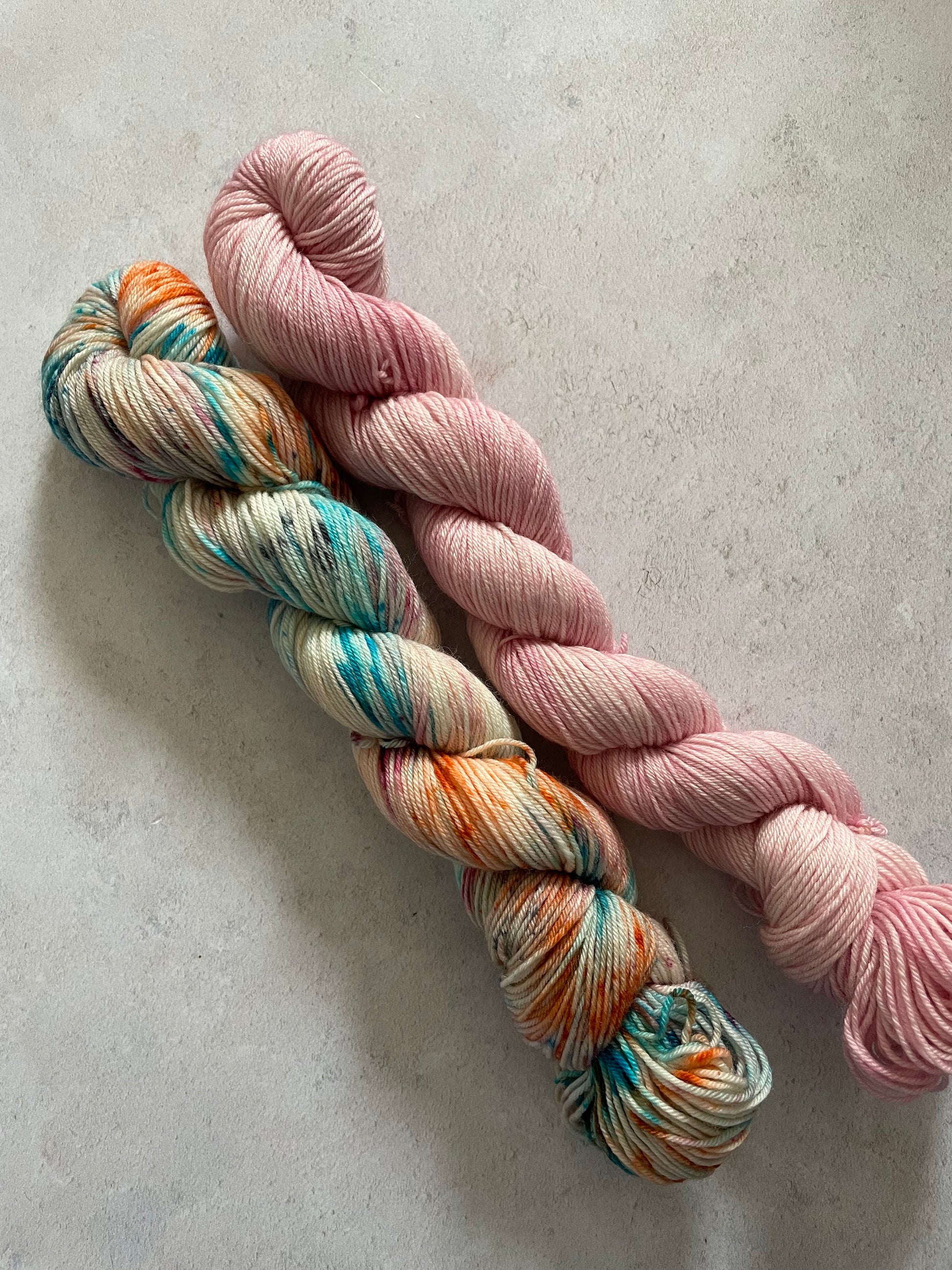 One 50g variegated blue orange and pink skein and one 50g pink skein