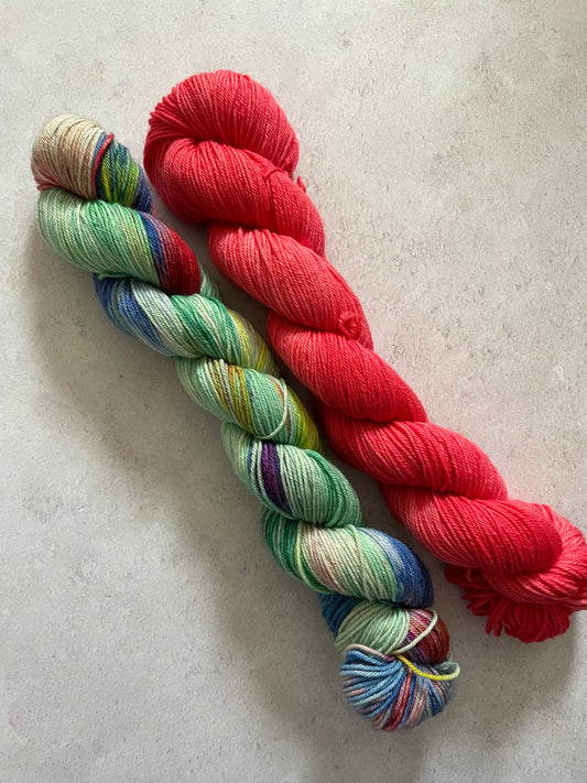 One 50g variegated green and multicoloured skein and one 50g red skein