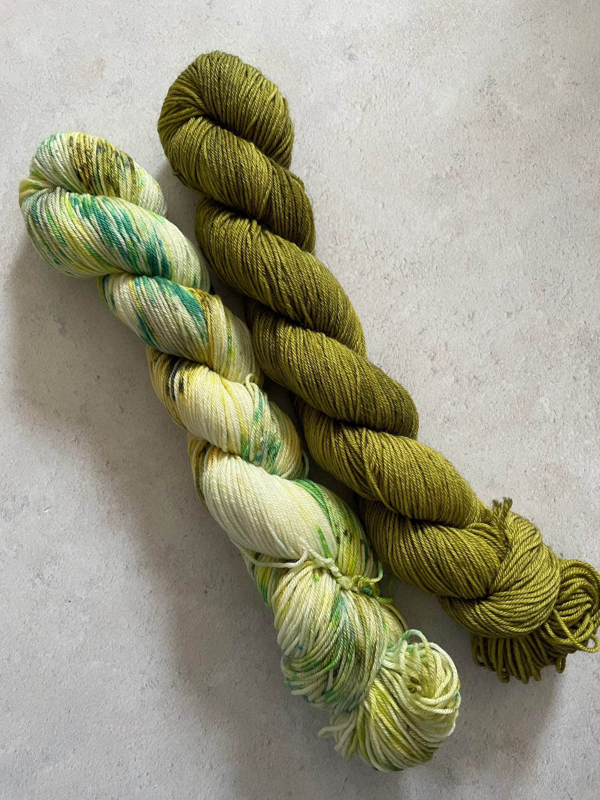 One 50g variegated green and cream skein and one 50g olive green skein