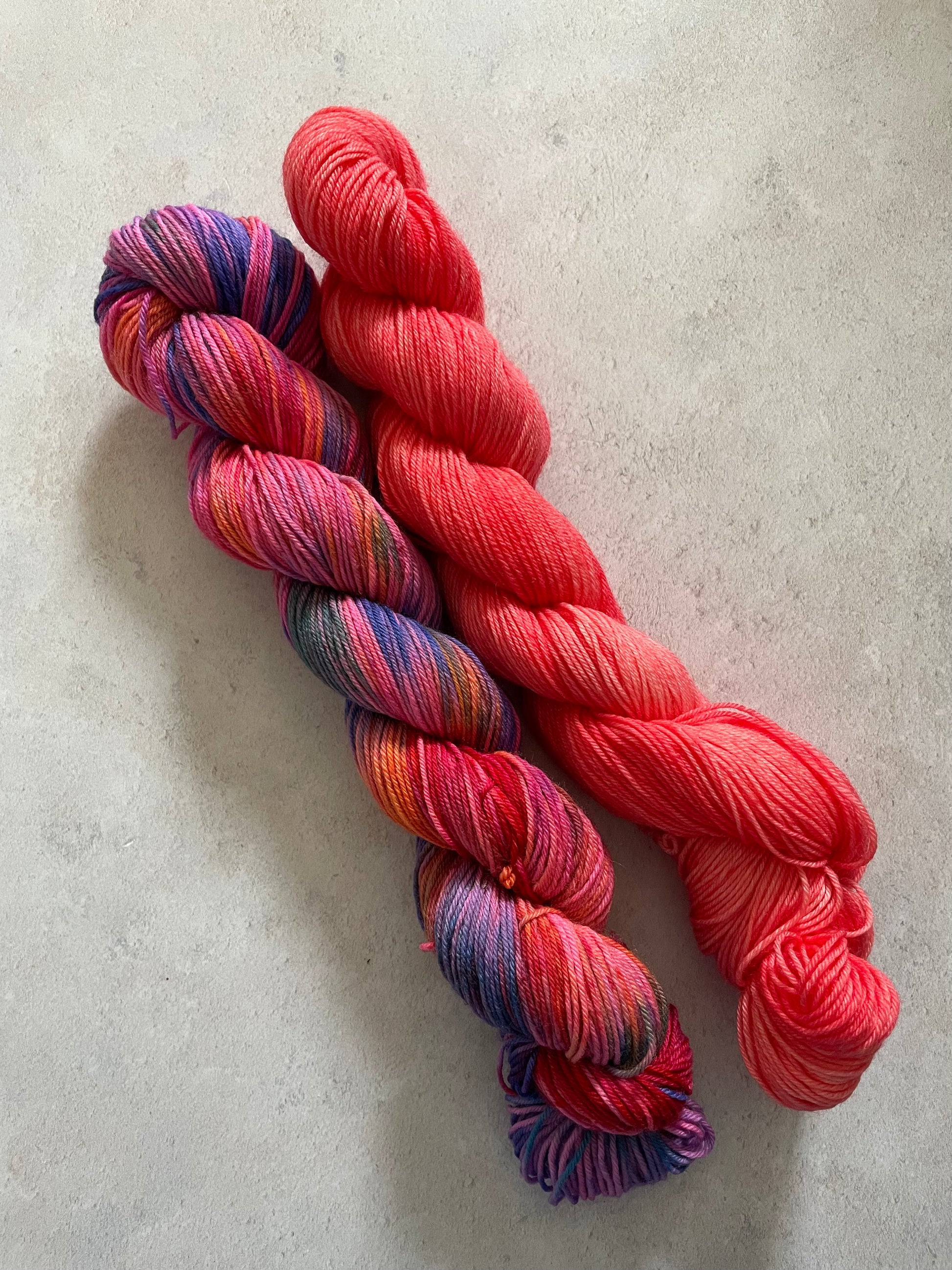 One 50g variegated red and multicoloured skein and one 50g red skein