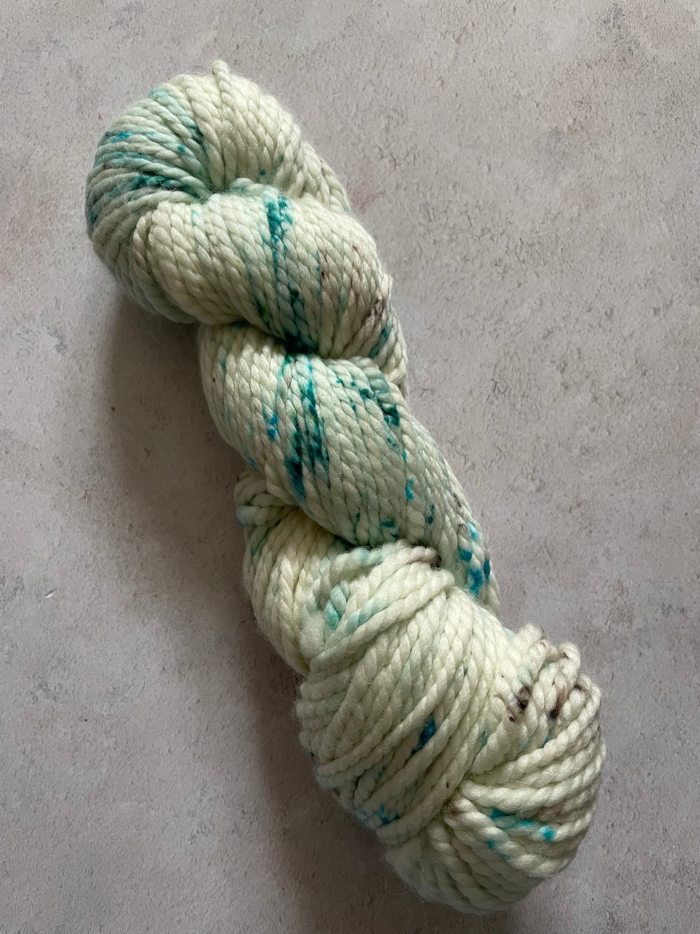 Chunky white skein with grey and teal speckles