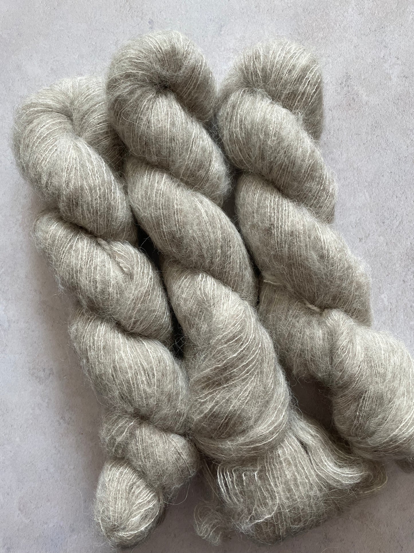 Three skeins of yak cloud, a grey fluffy yarn