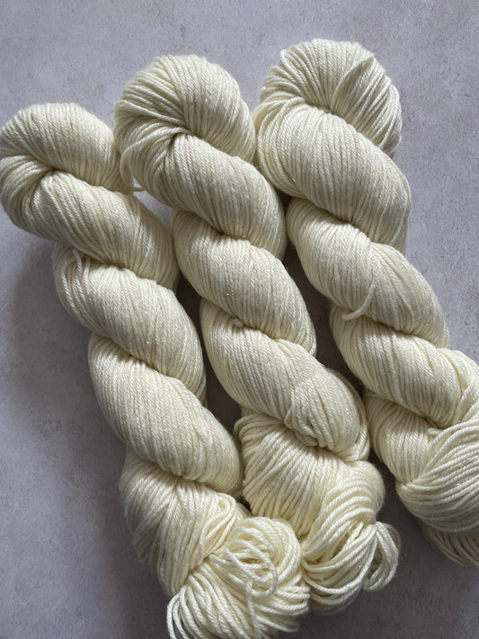 Three skeins of undyed gold sparkle double knitting yarn