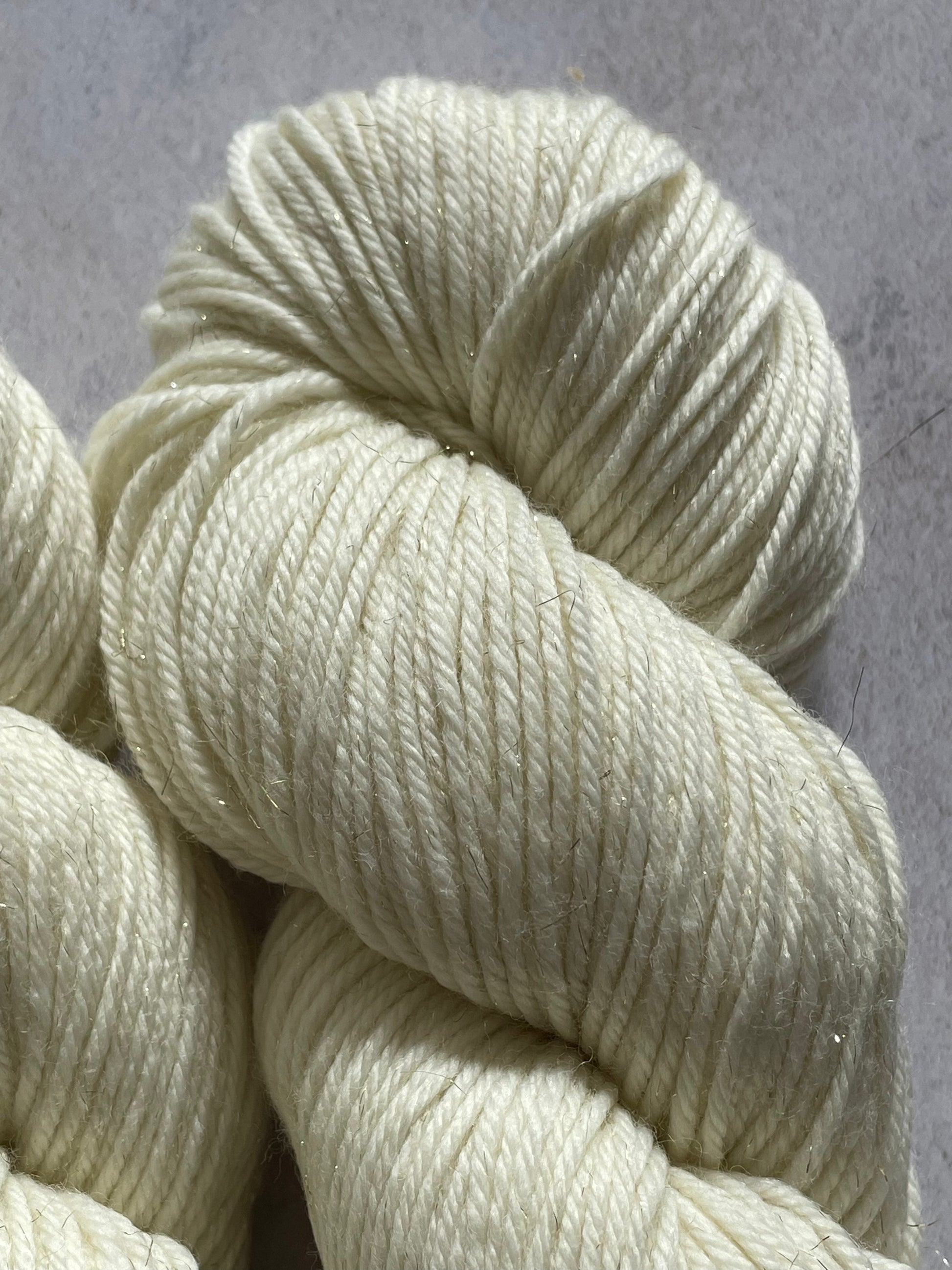 A close up of undyed gold sparkle double knitting yarn