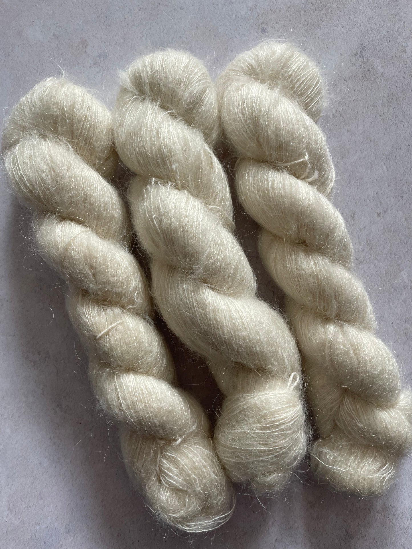 Three skeins of undyed kid mohair and silk yarn