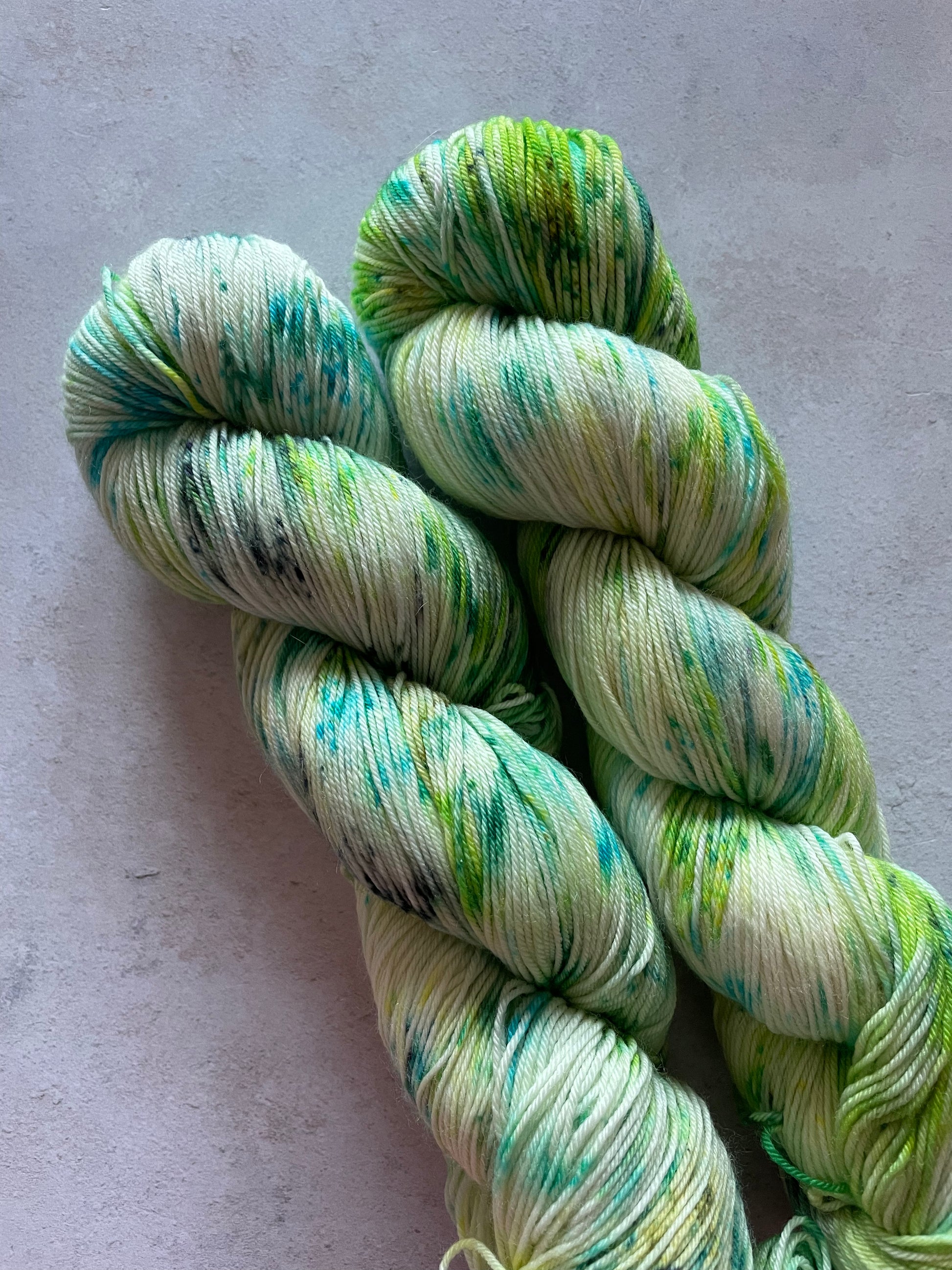 2 skeins of yarn speckled with green and turquoise