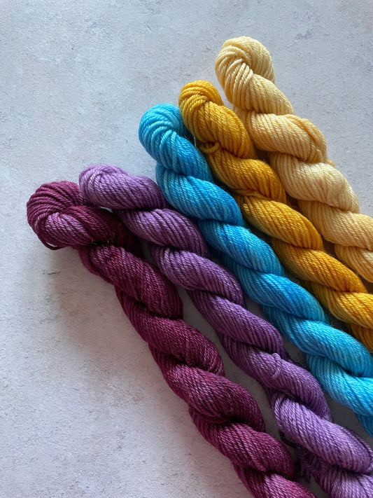 5 mini skeins in shades of purple blue and yellow