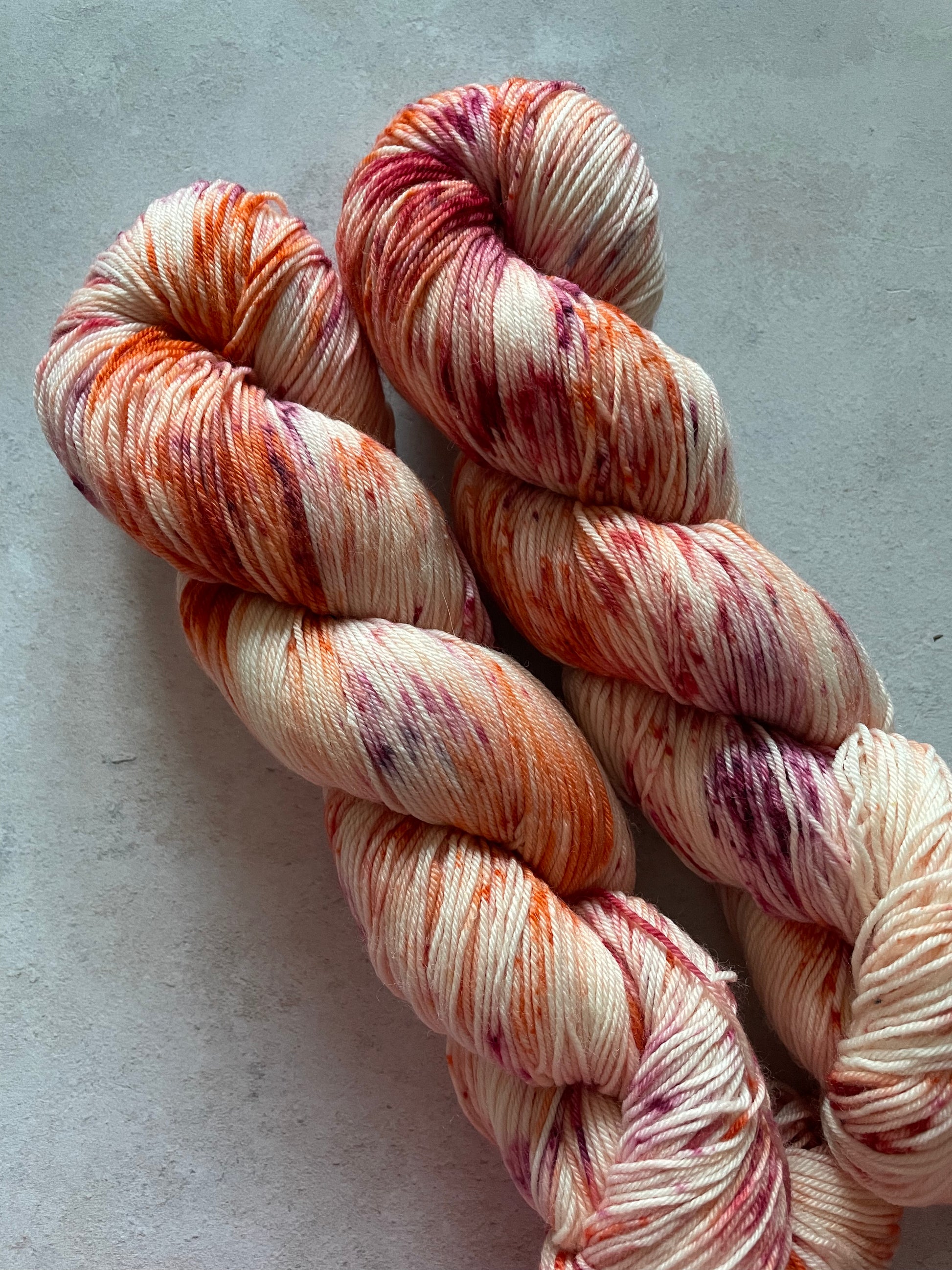 2 skeins of yarn speckled with red orange and burgundy