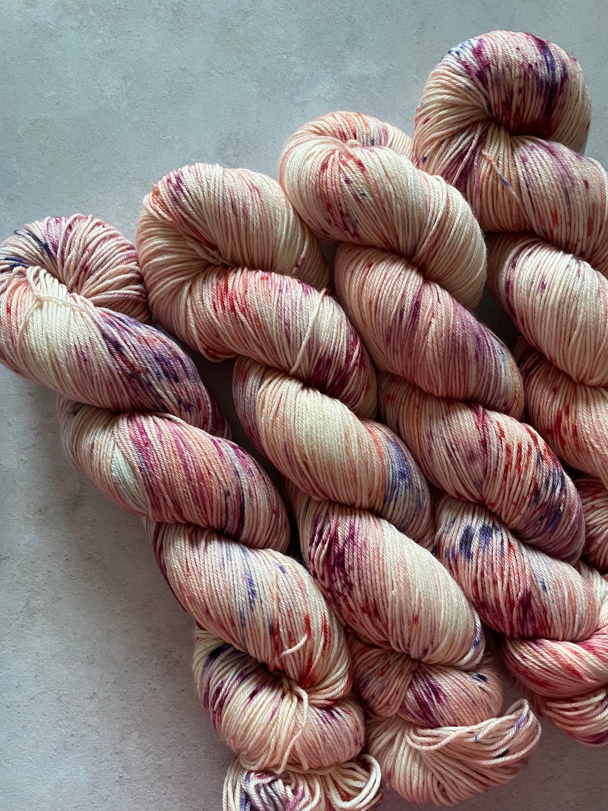 4 skeins of pink yarn lightly speckled with blue and burgundy