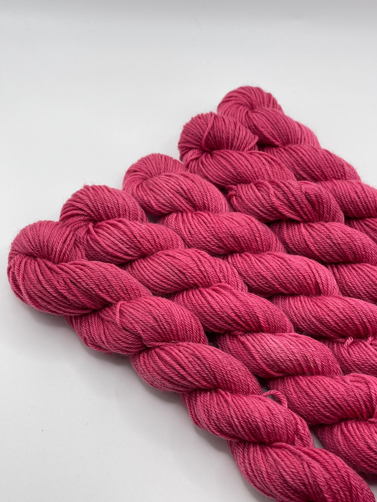 Deep pink yarn mini skeins on a white background