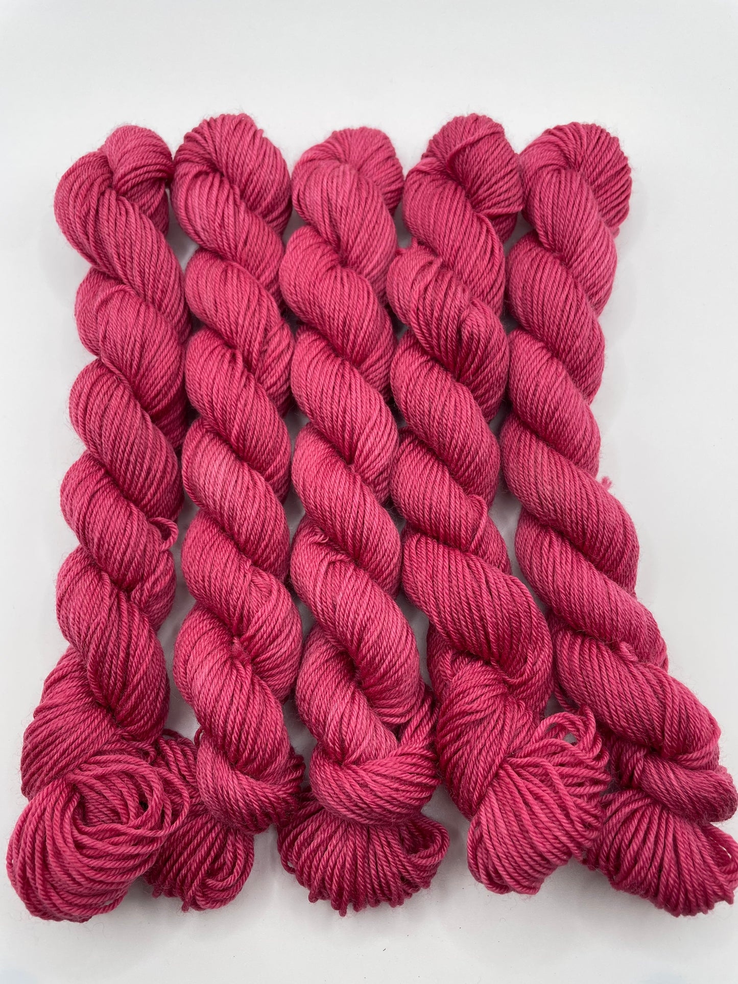Deep pink yarn mini skeins on a white background