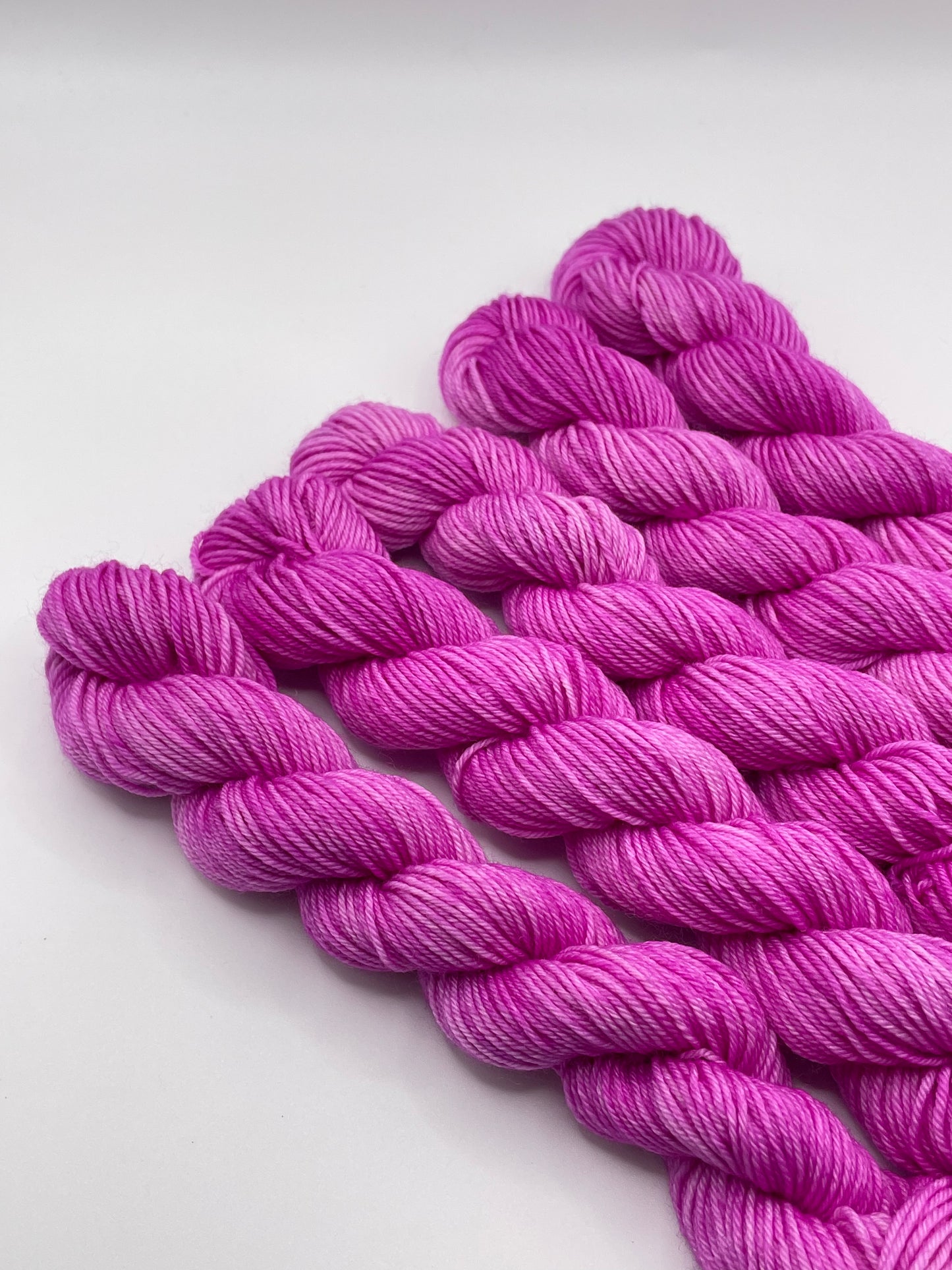 Purply pink yarn mini skeins on a white background