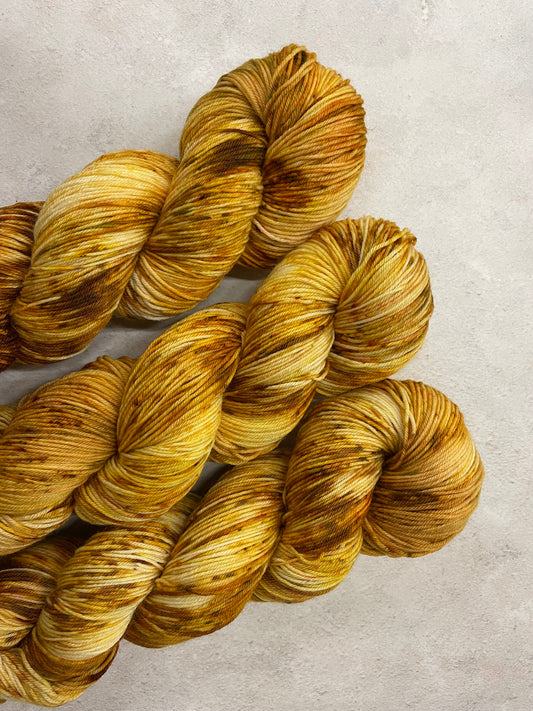 3 skeins of golden yellow sock yarn with gold and brown speckles