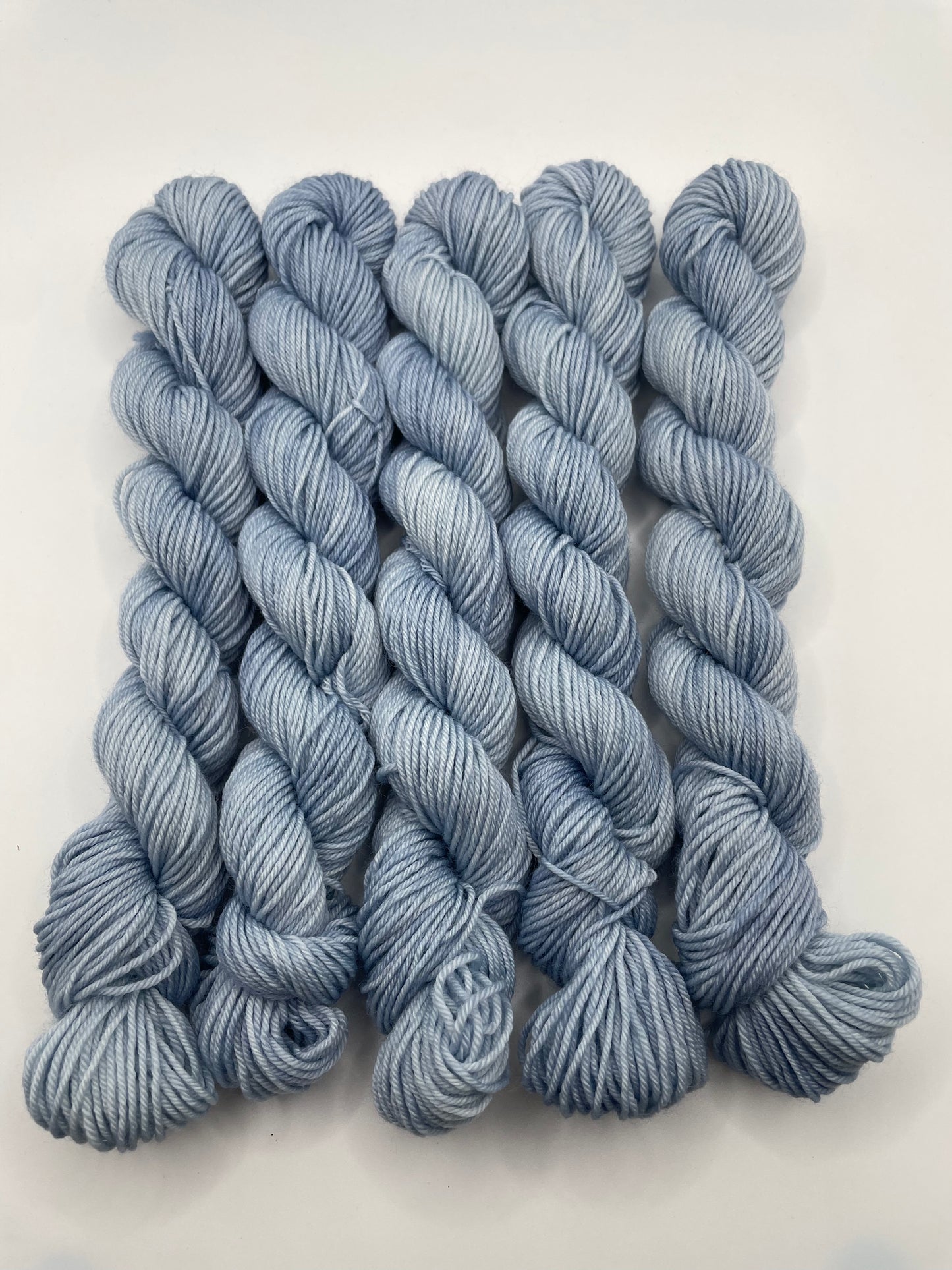 Pale blue yarn mini skeins on a white background