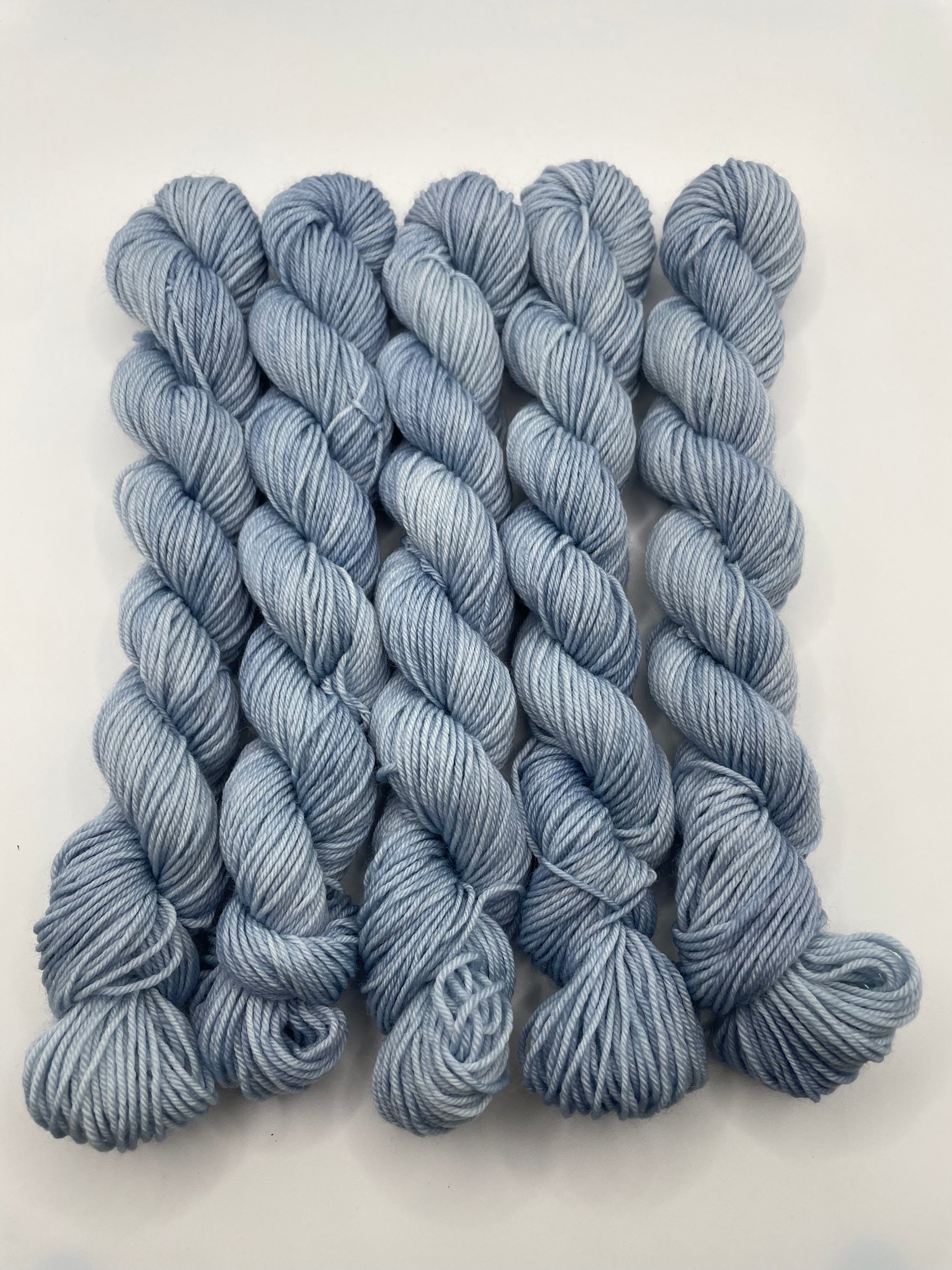 Pale blue yarn mini skeins on a white background