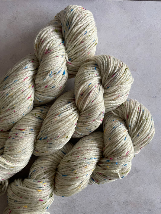 3 skeins of neutral double knitting yarn with green pink and blue neps