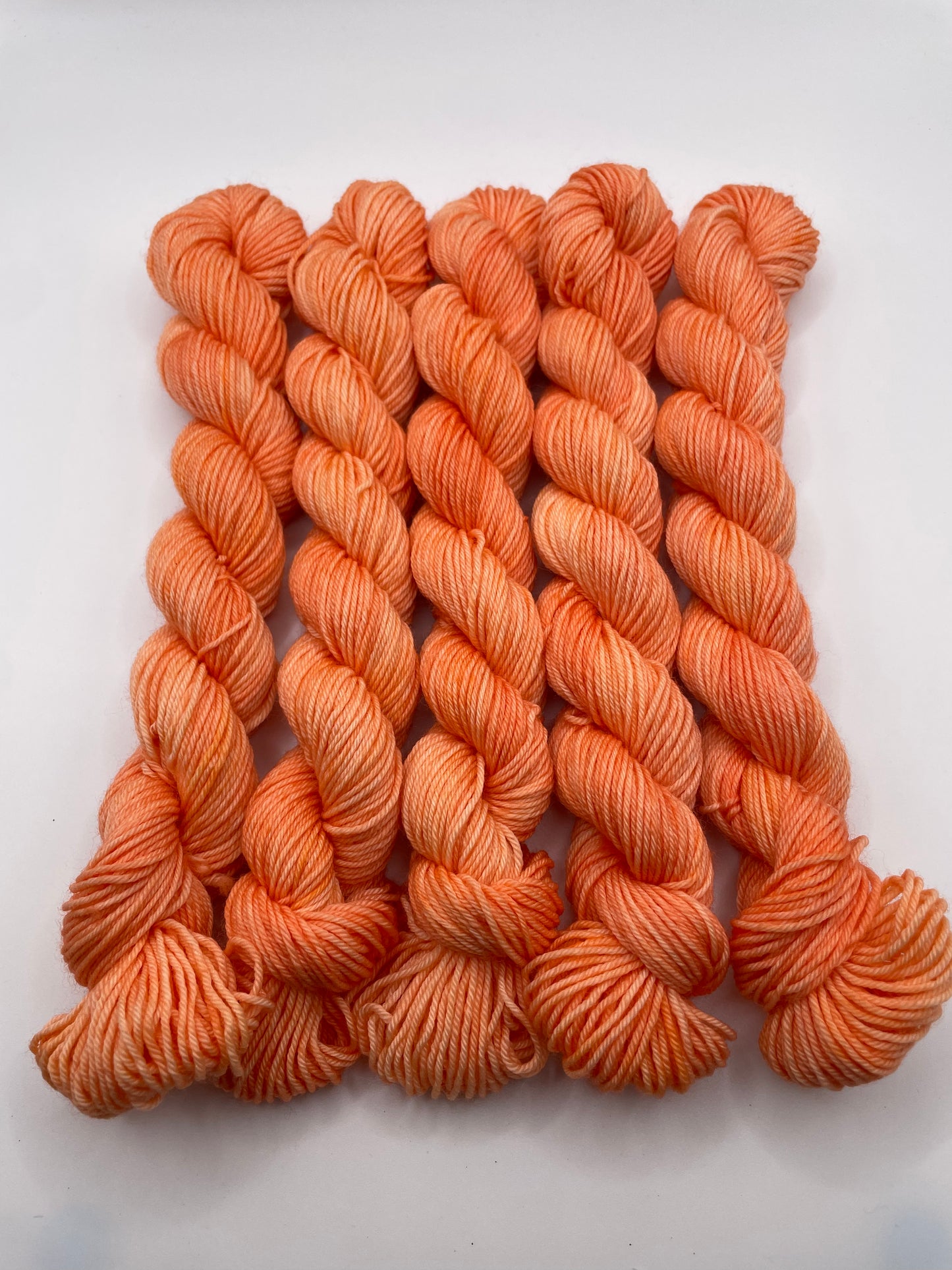 Orange yarn mini skeins on a white background