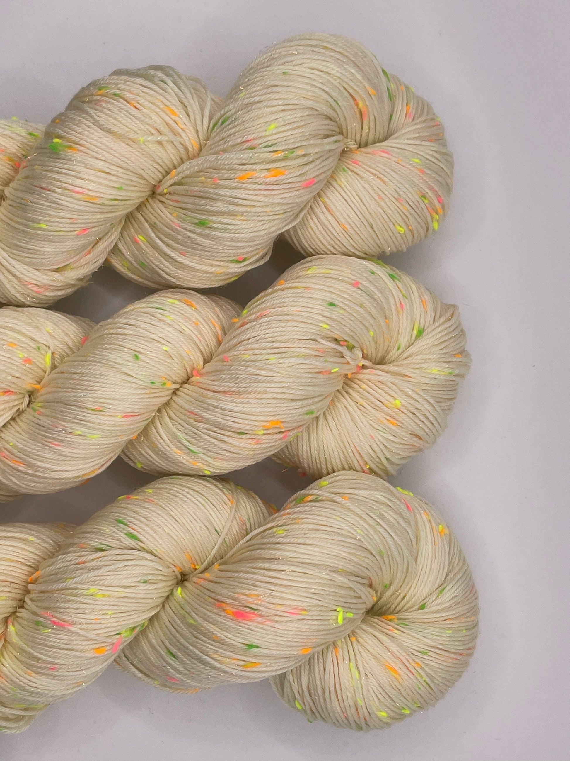 Undyed skeins of yarn with neon donegal neps and iridescent stellina