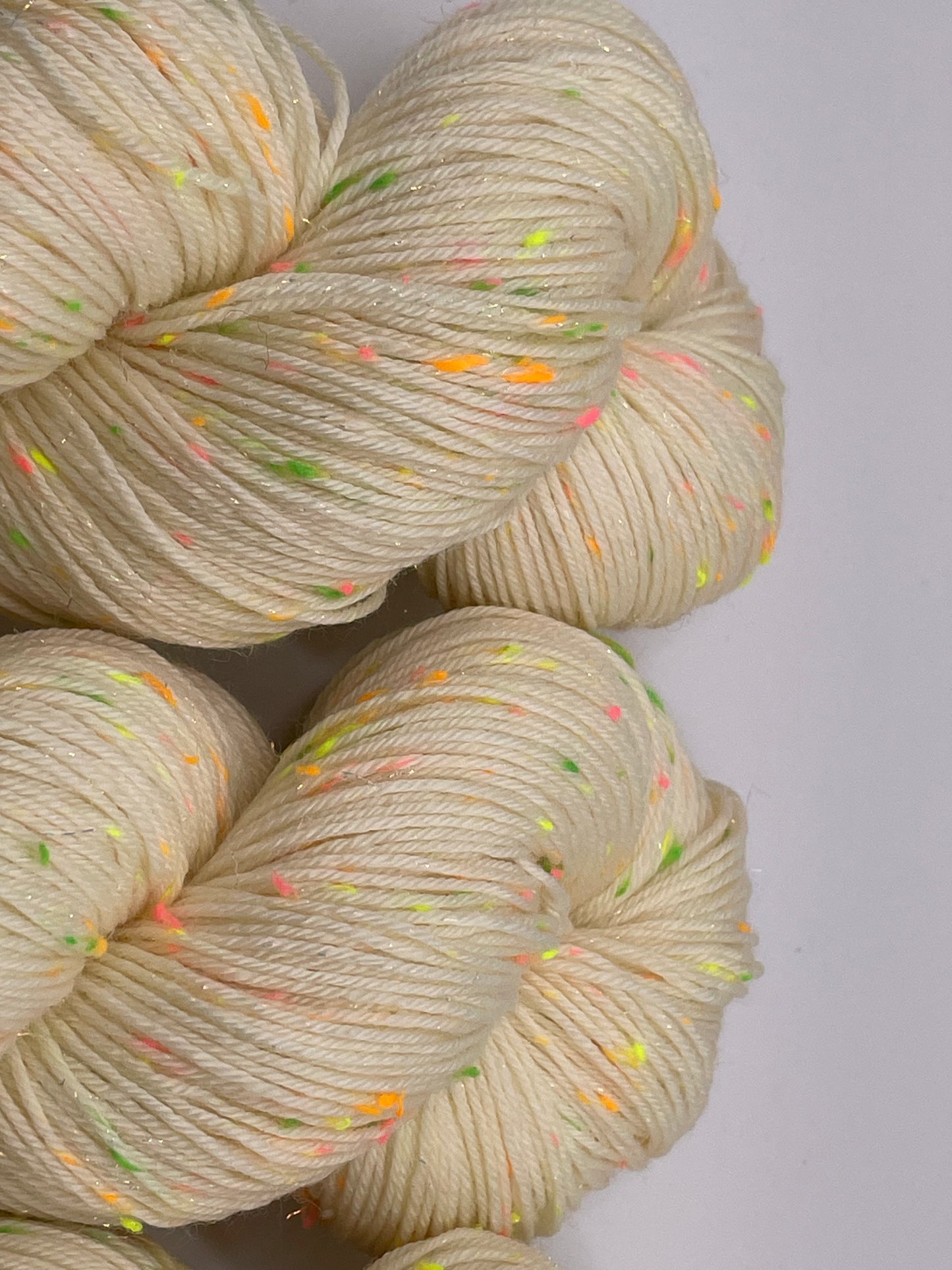 Undyed skeins of yarn with neon donegal neps and iridescent stellina