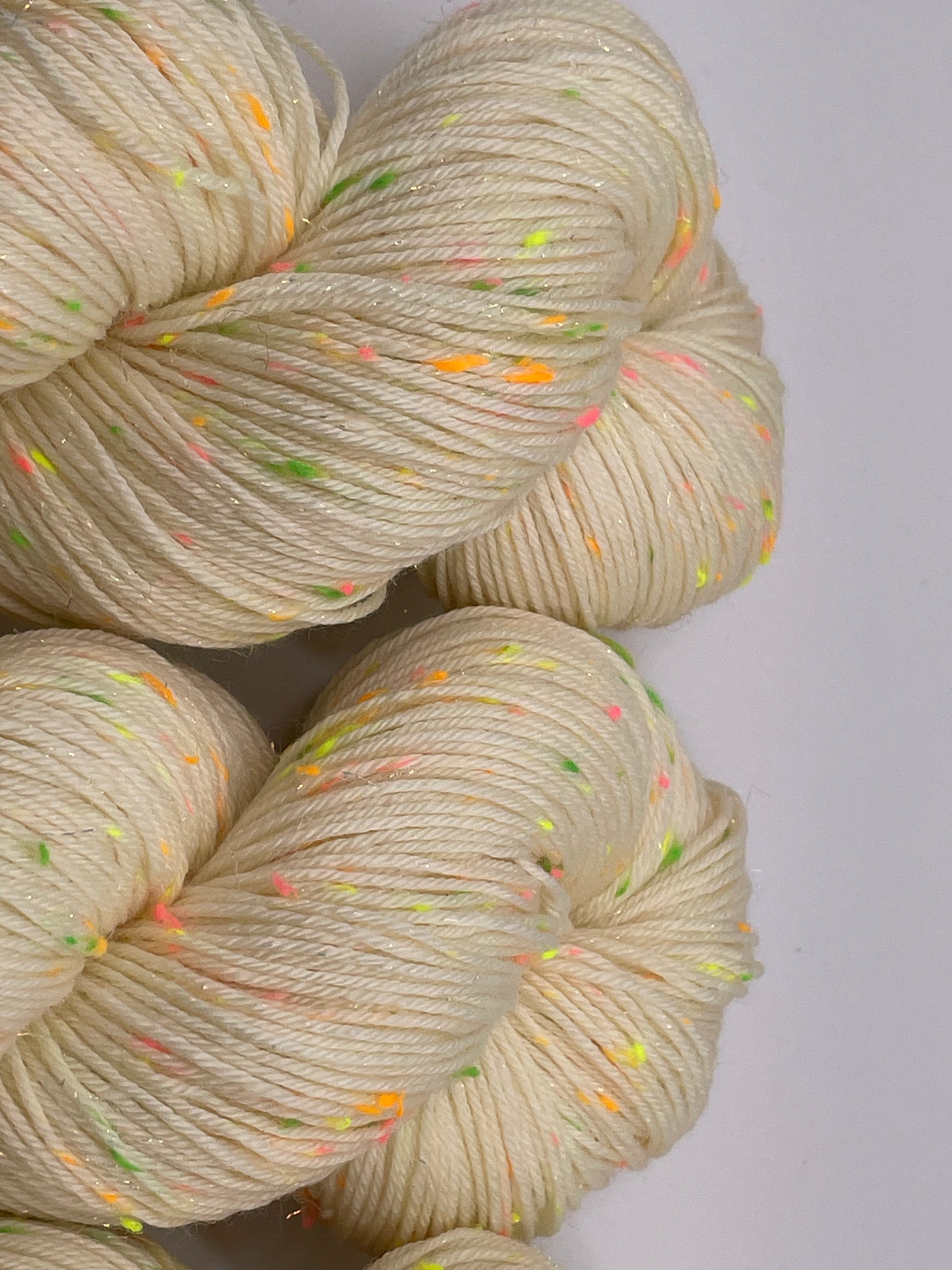 Undyed skeins of yarn with neon donegal neps and iridescent stellina