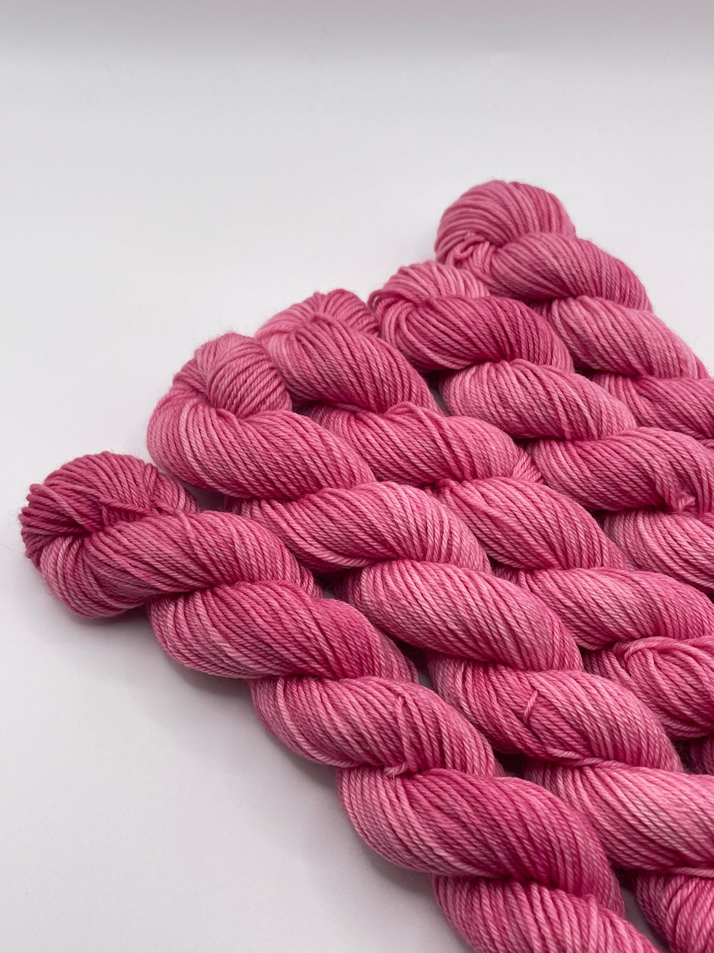 Pink yarn mini skeins on a white background
