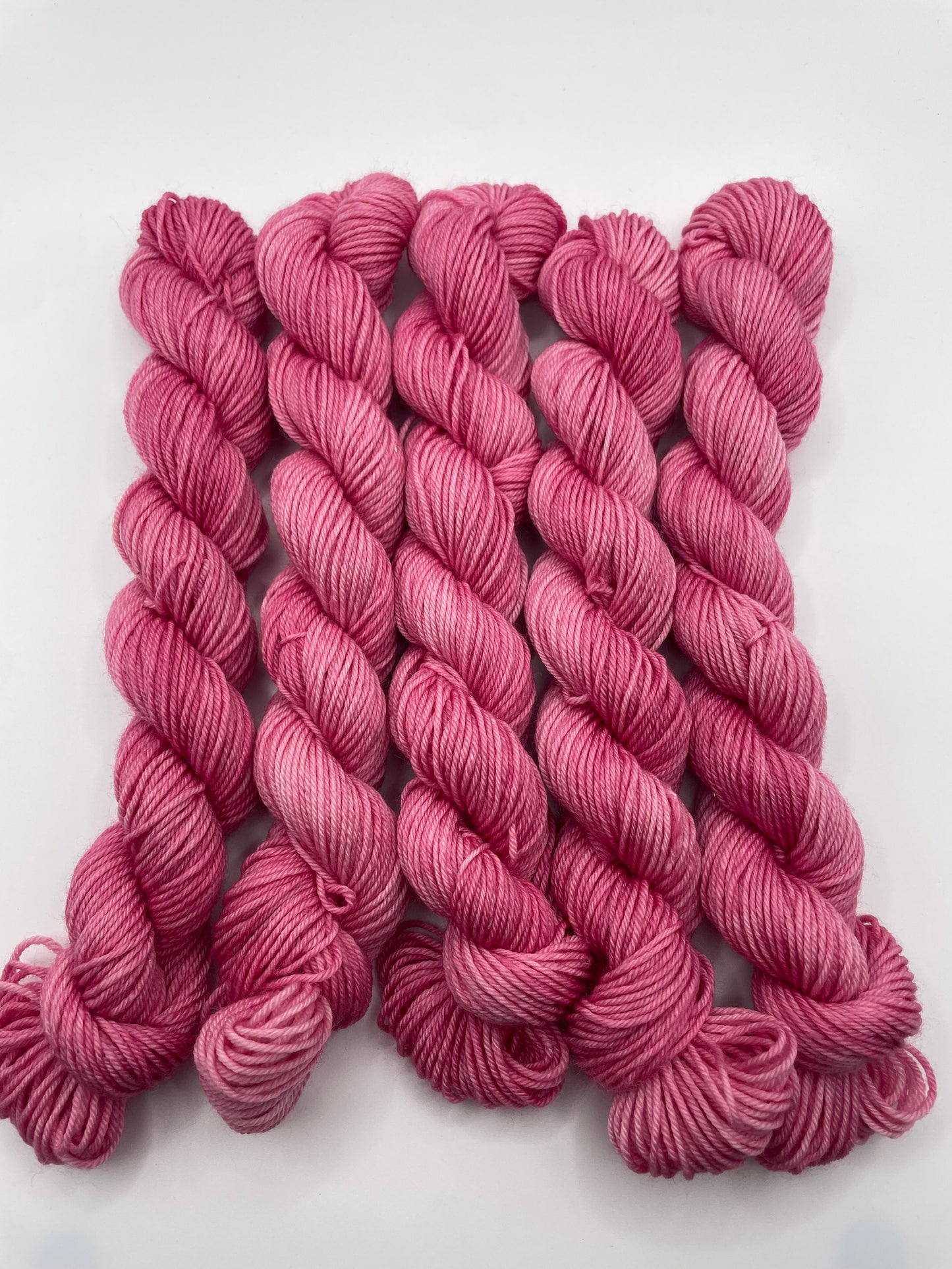 Pink yarn mini skeins on a white background