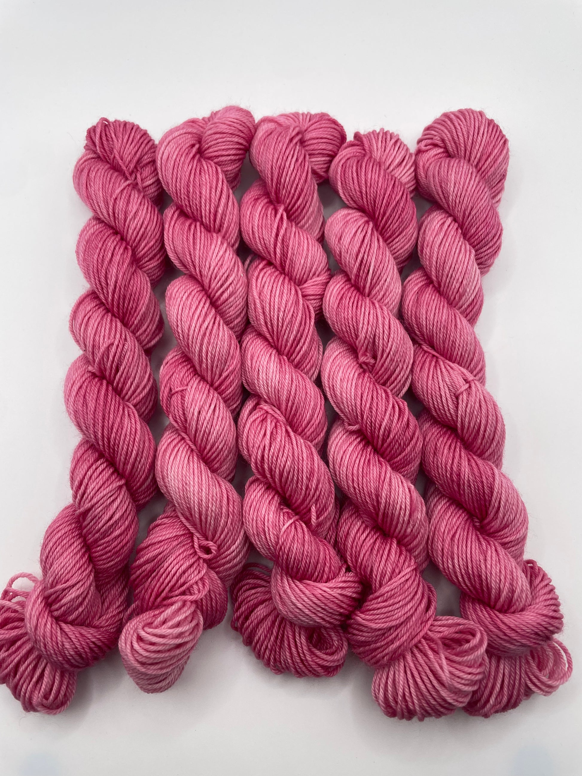 Pink yarn mini skeins on a white background