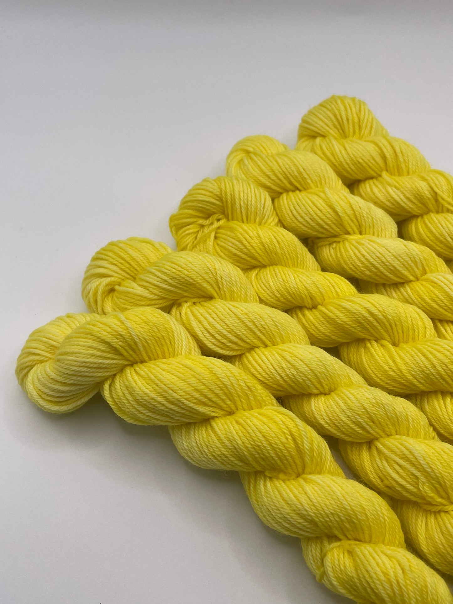 Yellow yarn mini skeins on a white background