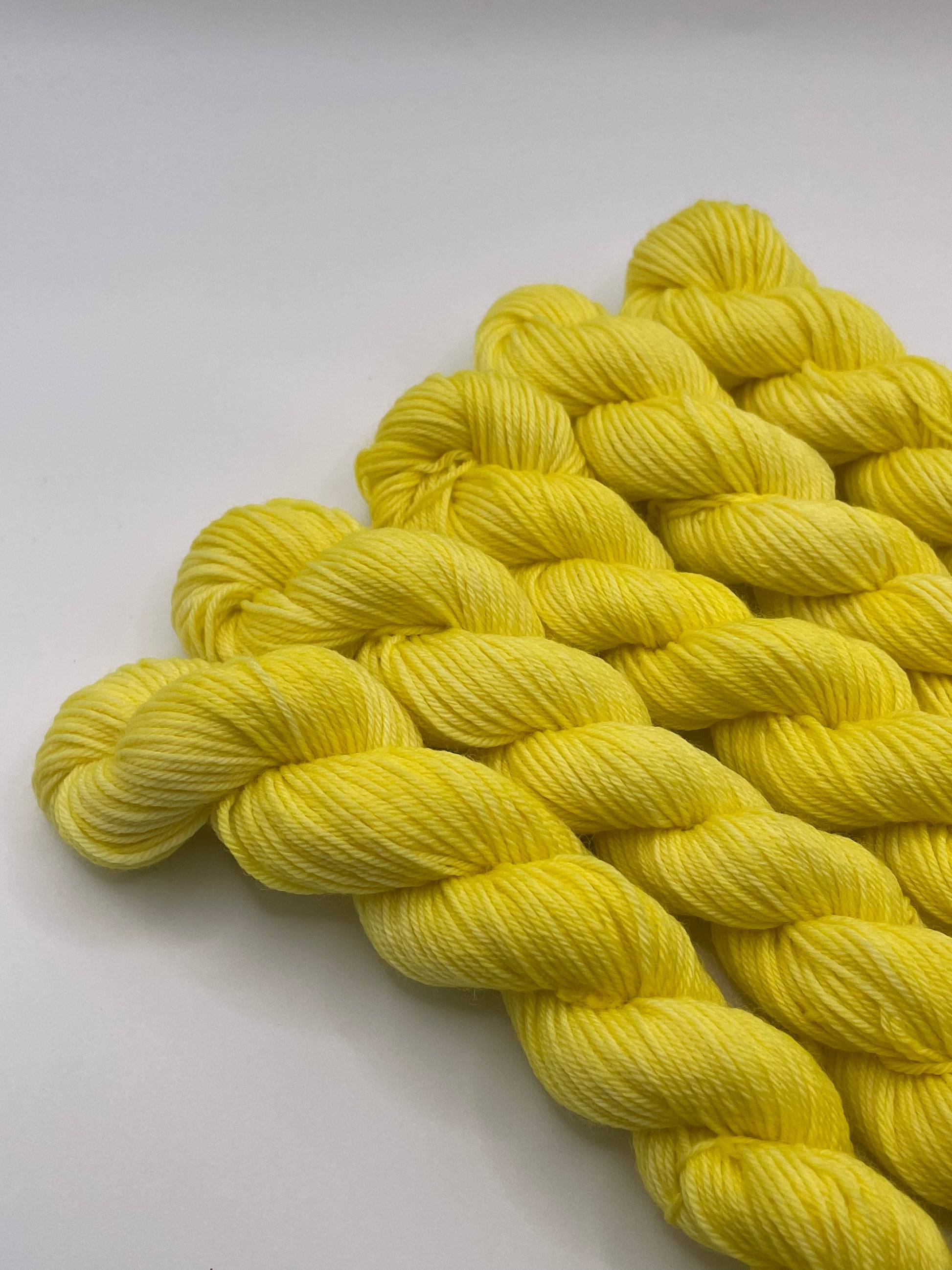Yellow yarn mini skeins on a white background