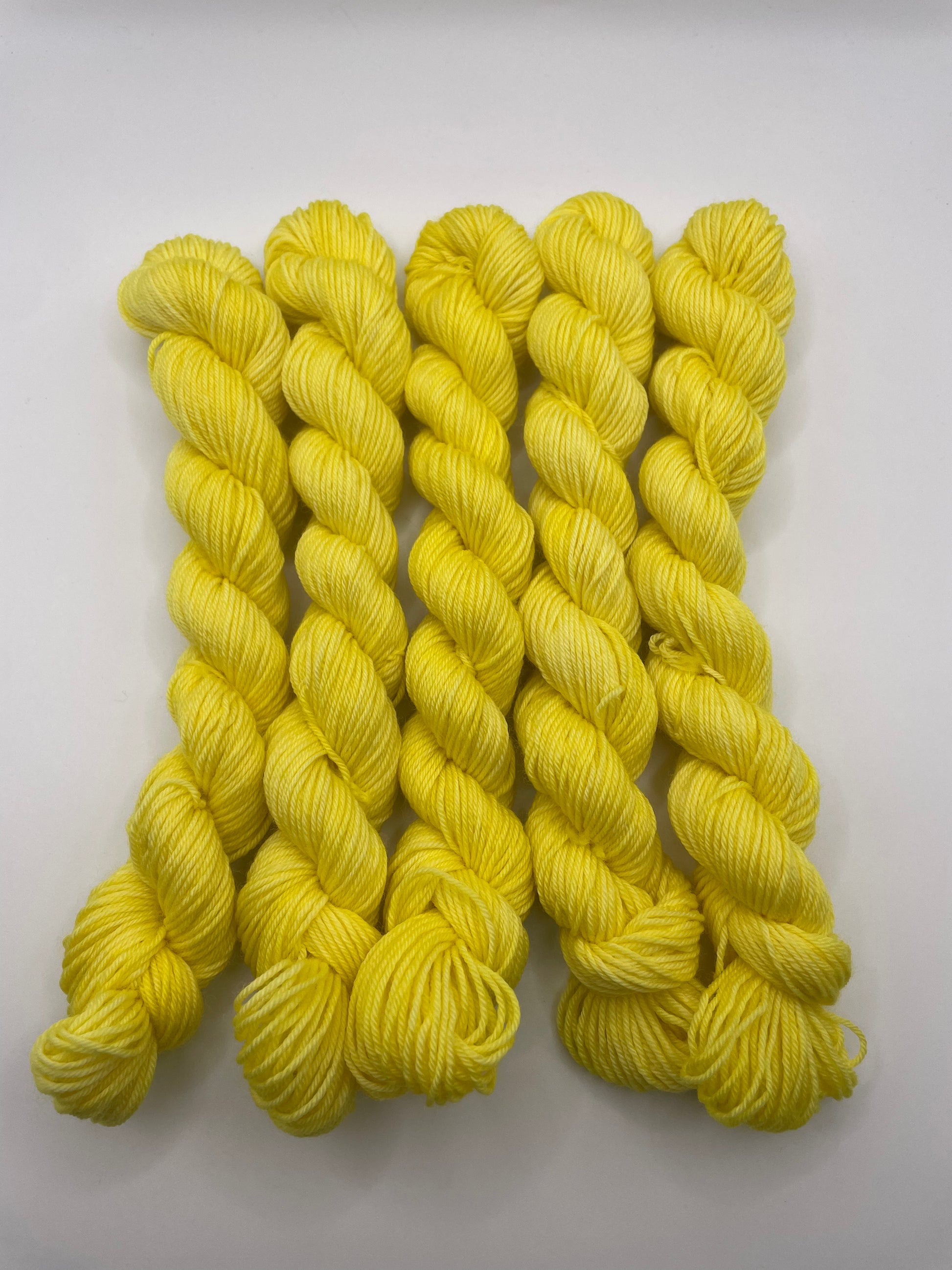 Yellow yarn mini skeins on a white background