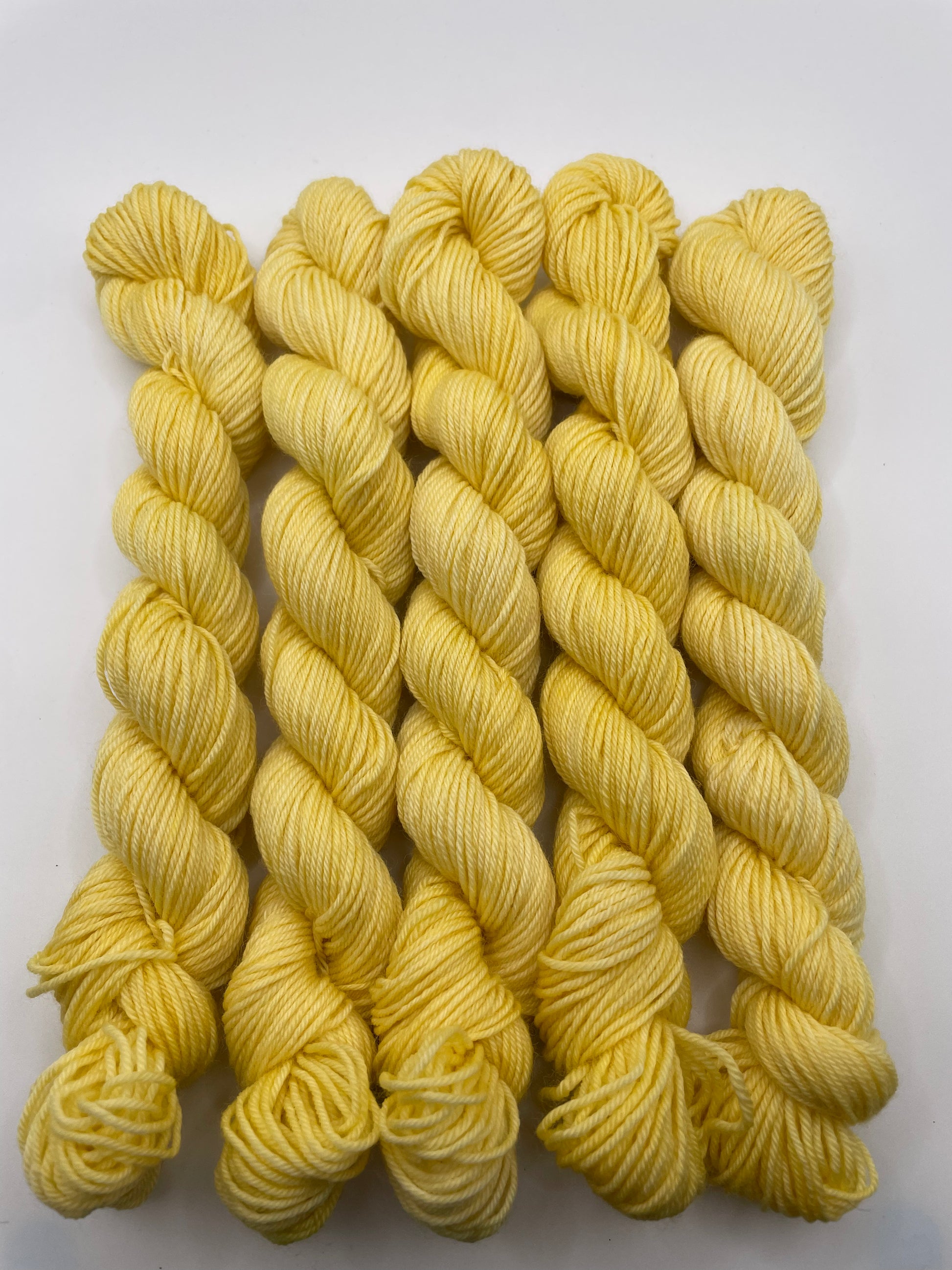 Yellow yarn mini skeins on a white background