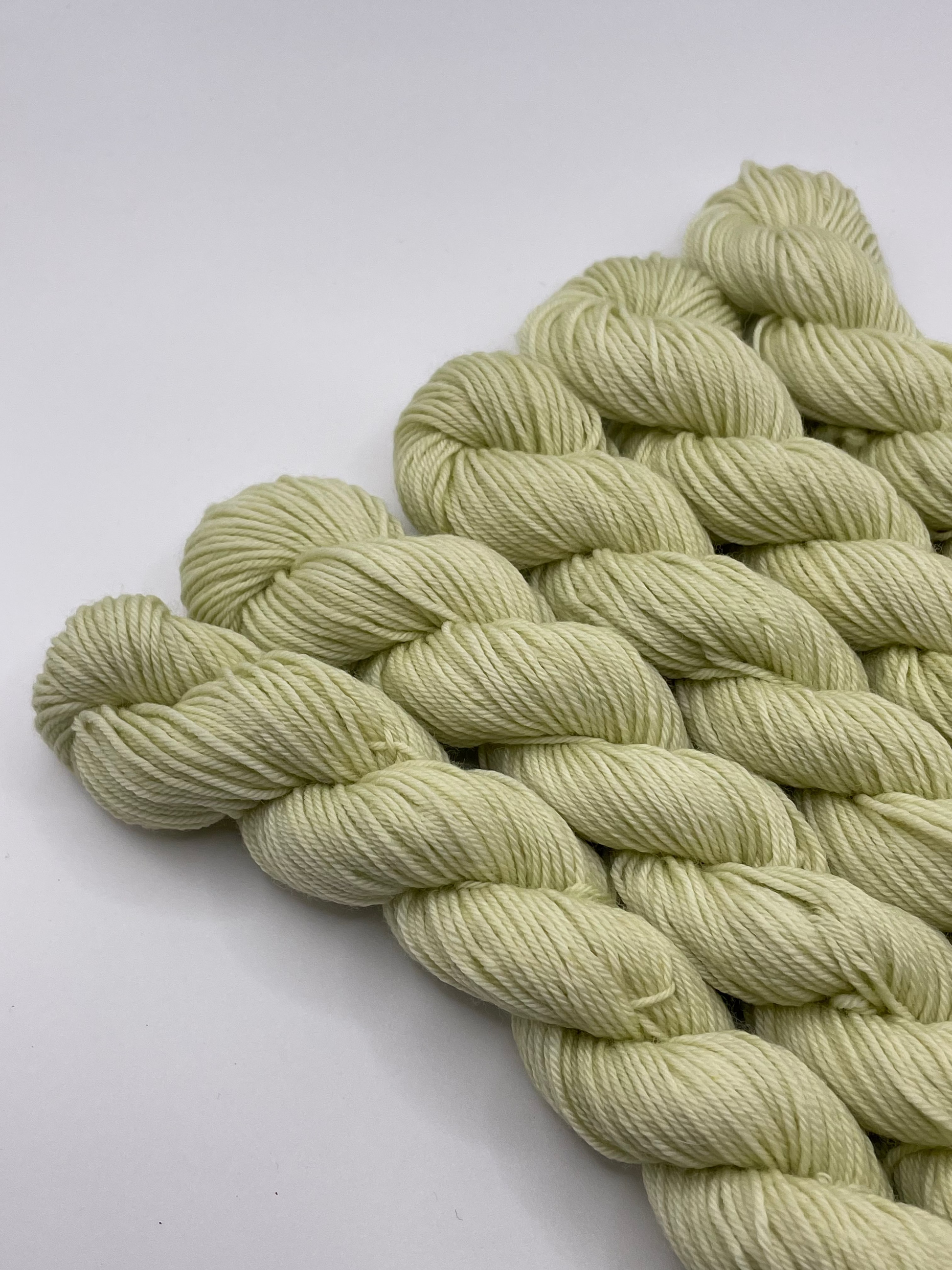 Pale green yarn mini skeins on a white background