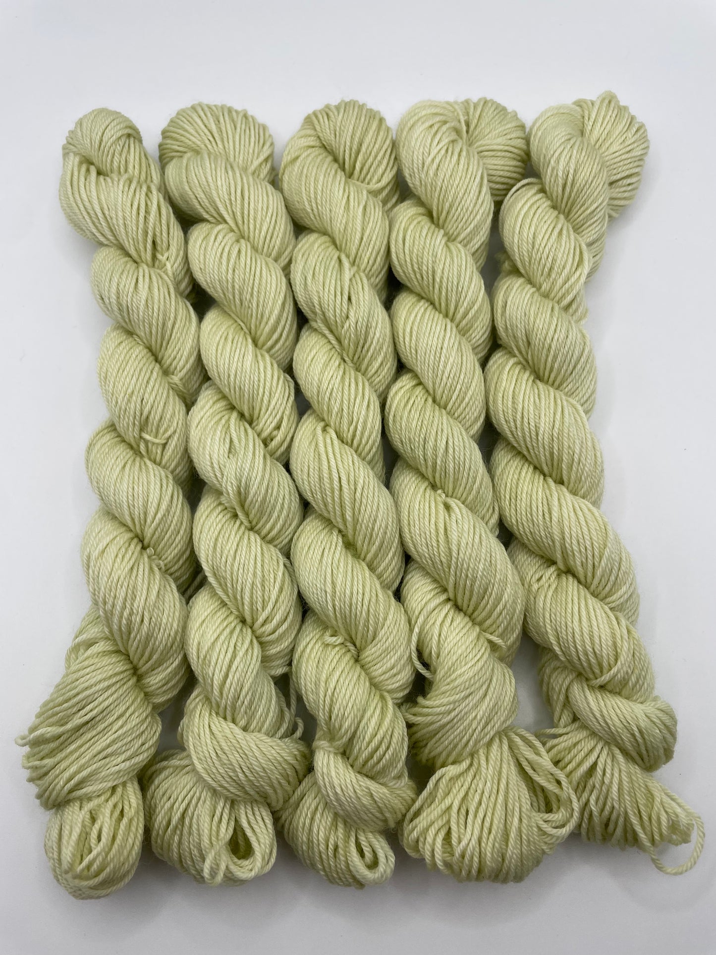 Pale green yarn mini skeins on a white background