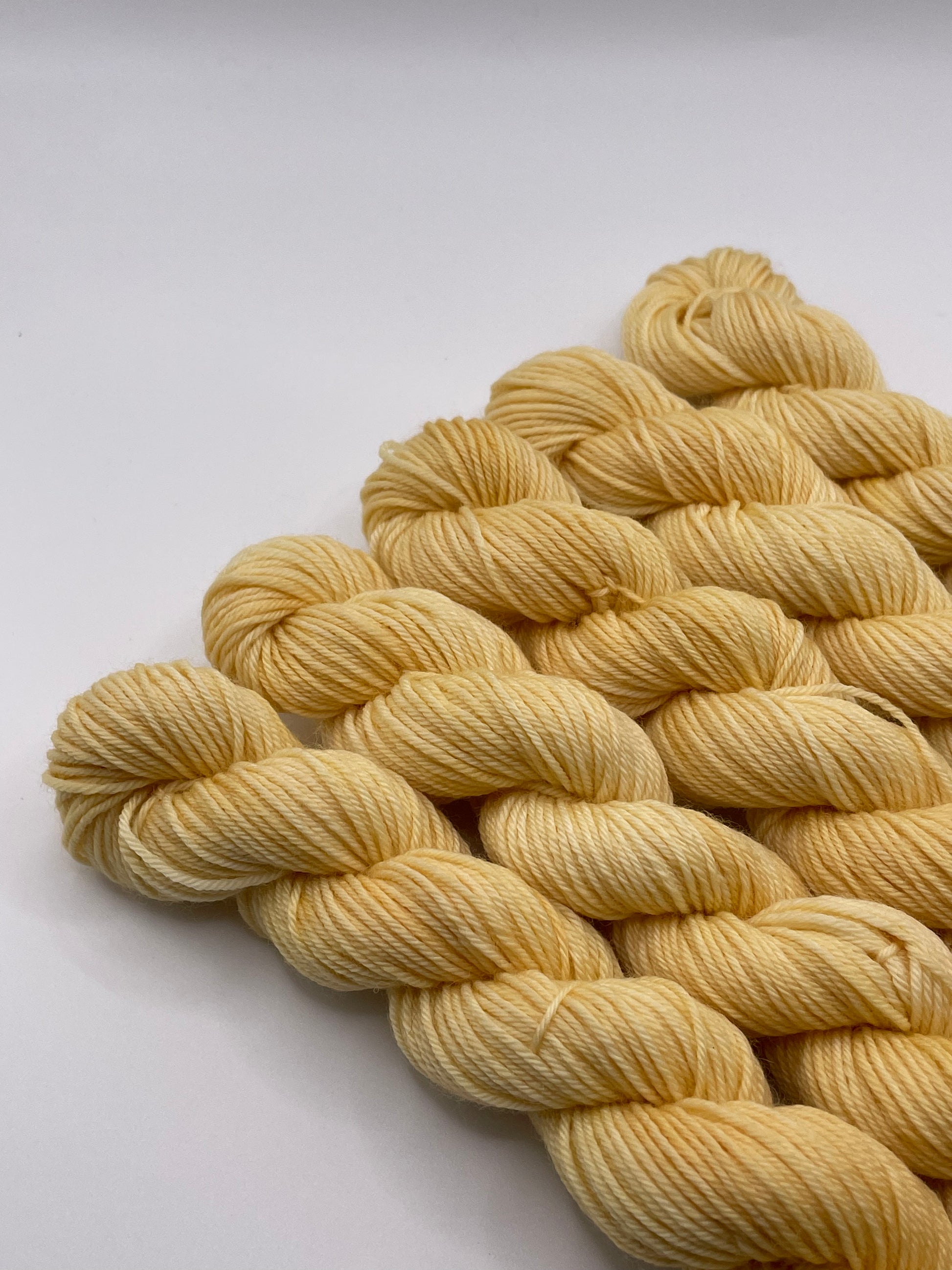 Yellow yarn mini skeins on a white background