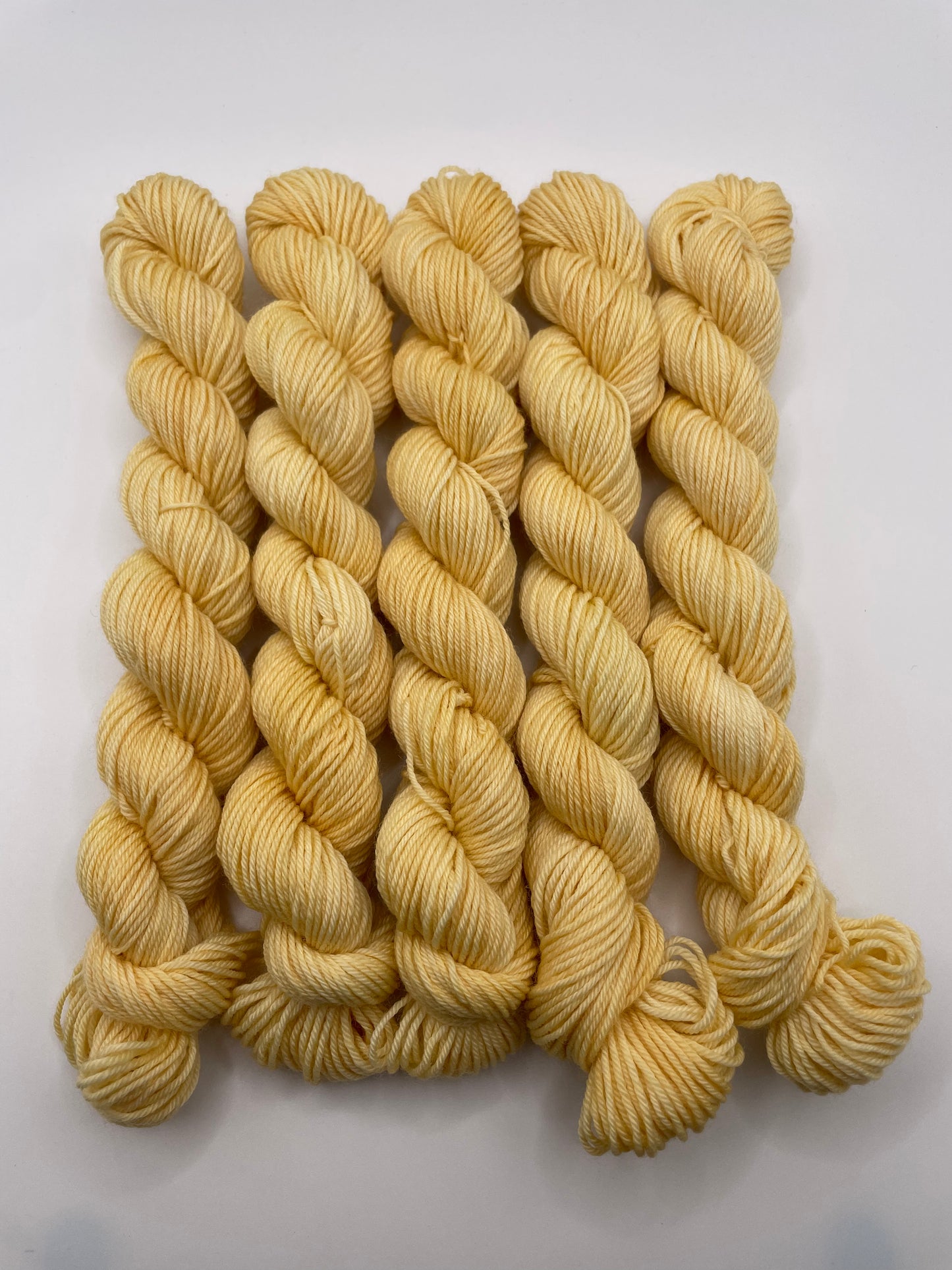 Yellow yarn mini skeins on a white background