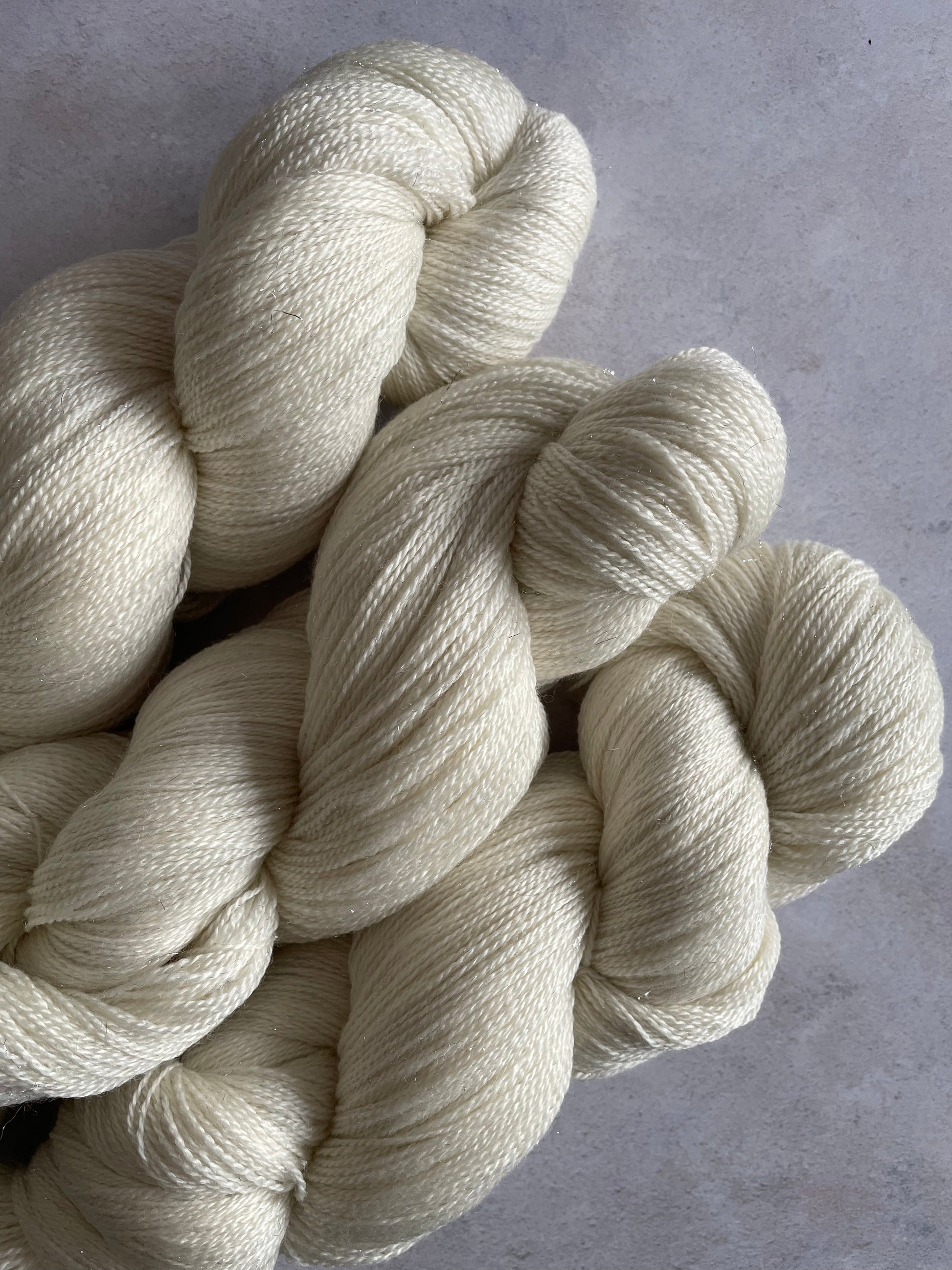 3 skeins of cream lace weight yarn with silver stellina sparkle