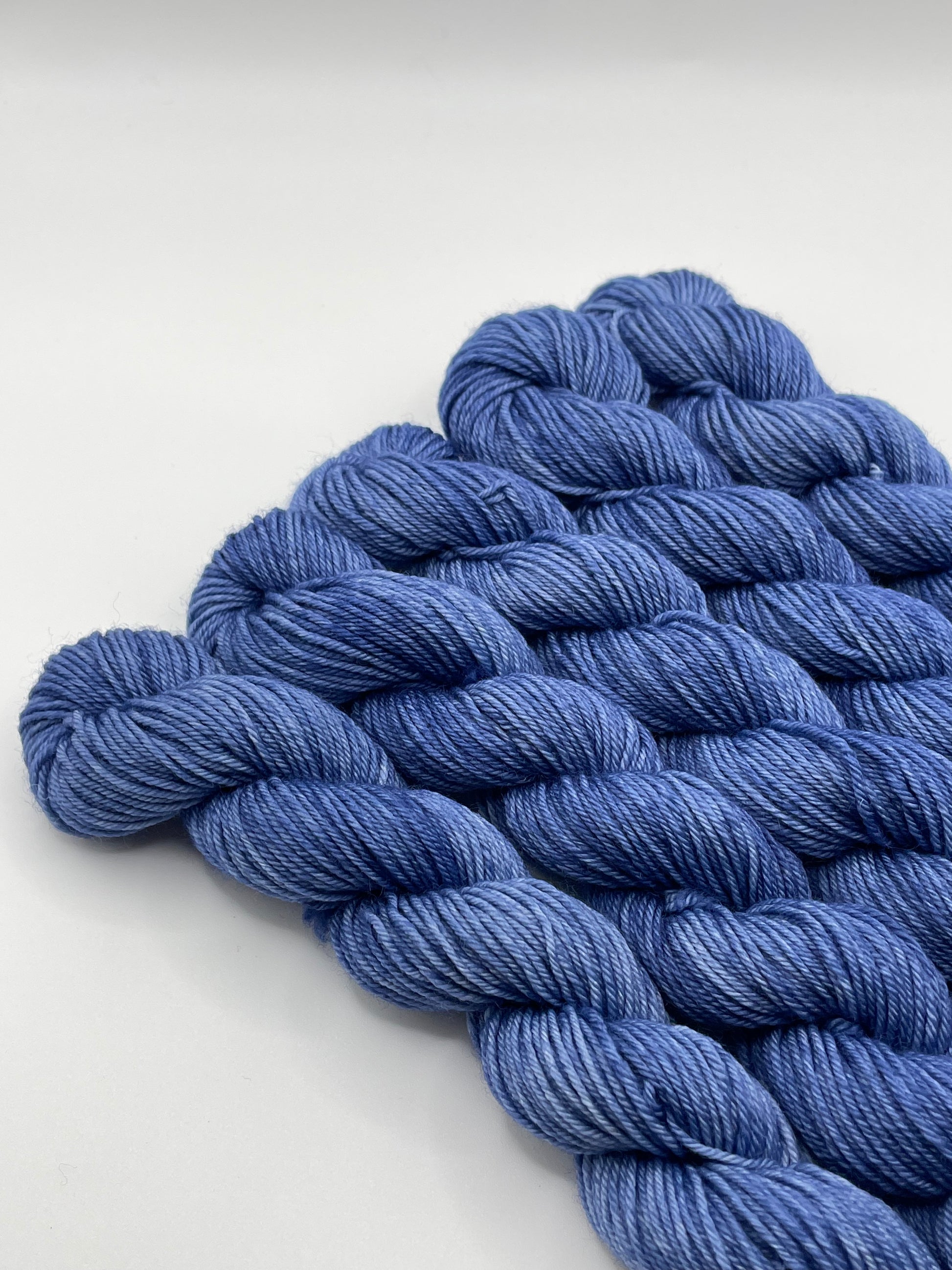 Deep blue yarn mini skeins on a white background