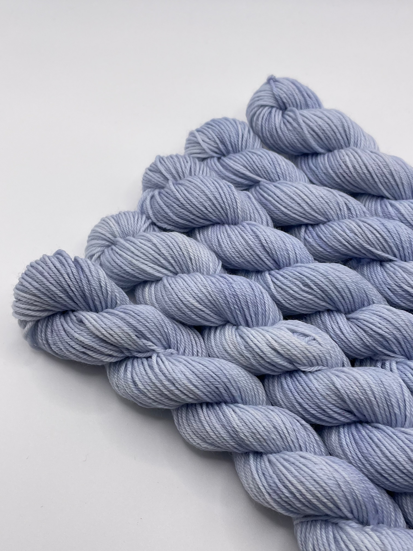 Pale blue grey yarn mini skeins on a white background