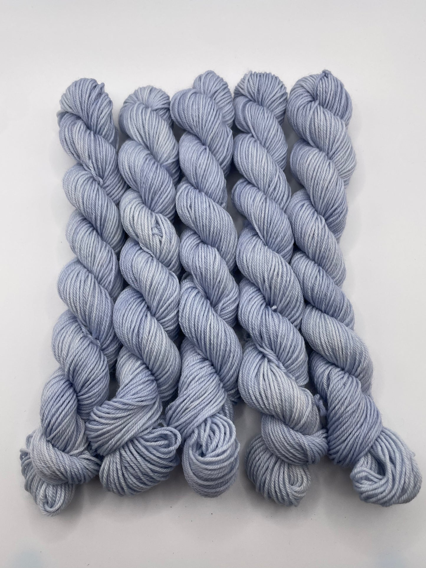 Pale blue grey yarn mini skeins on a white background