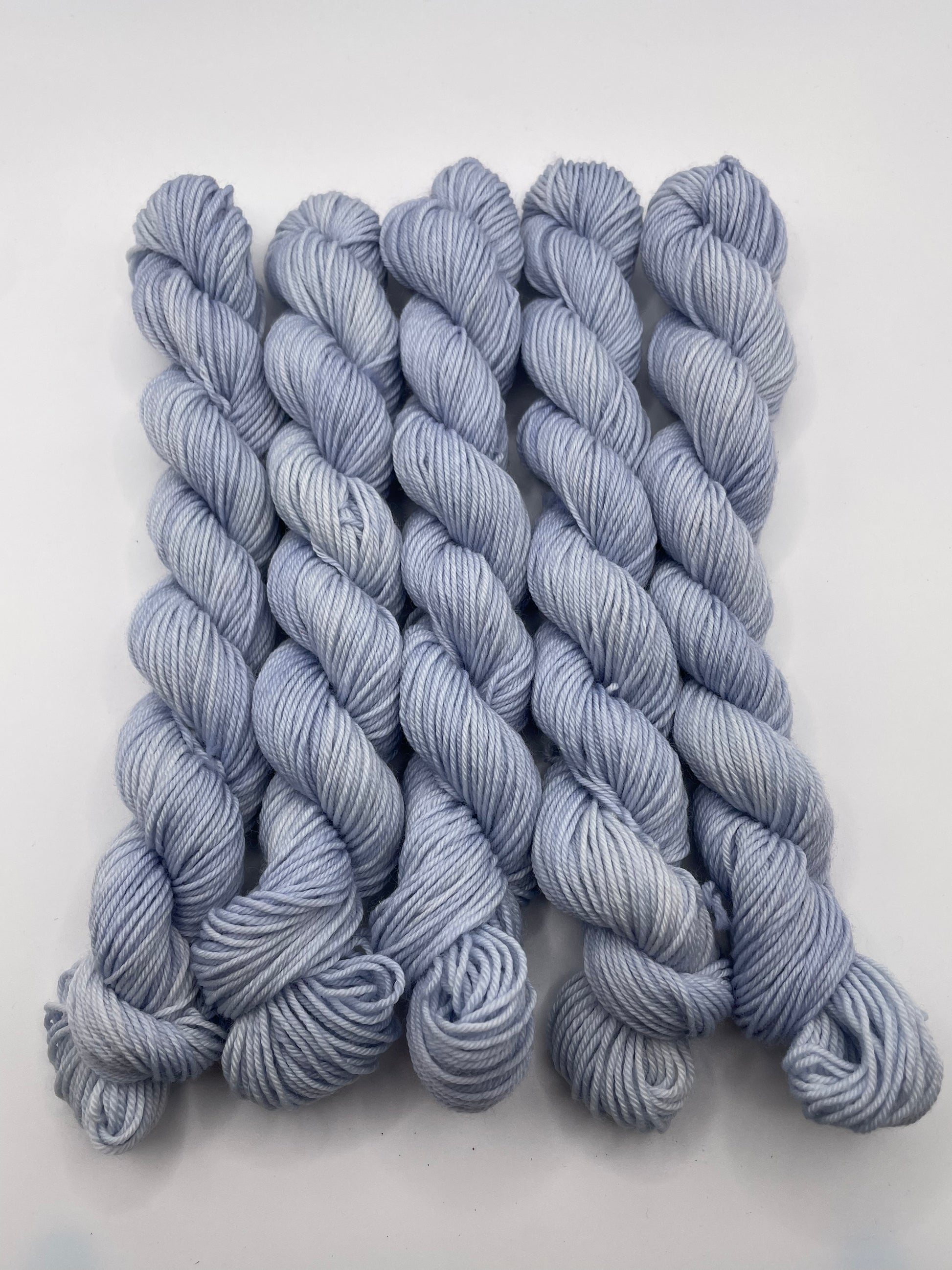 Pale blue grey yarn mini skeins on a white background