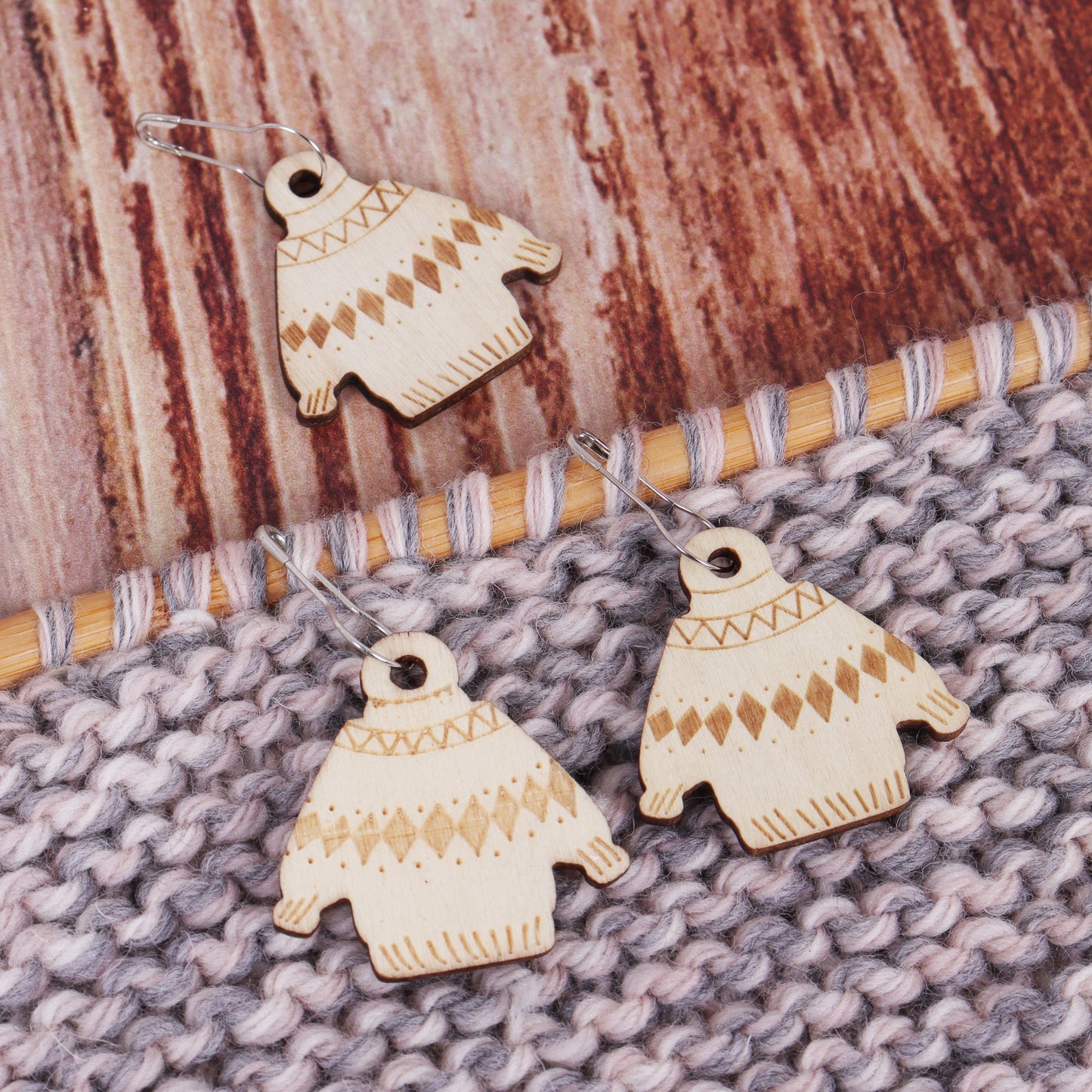 Wooden jumper stitch makers against a wooden background and knitted background